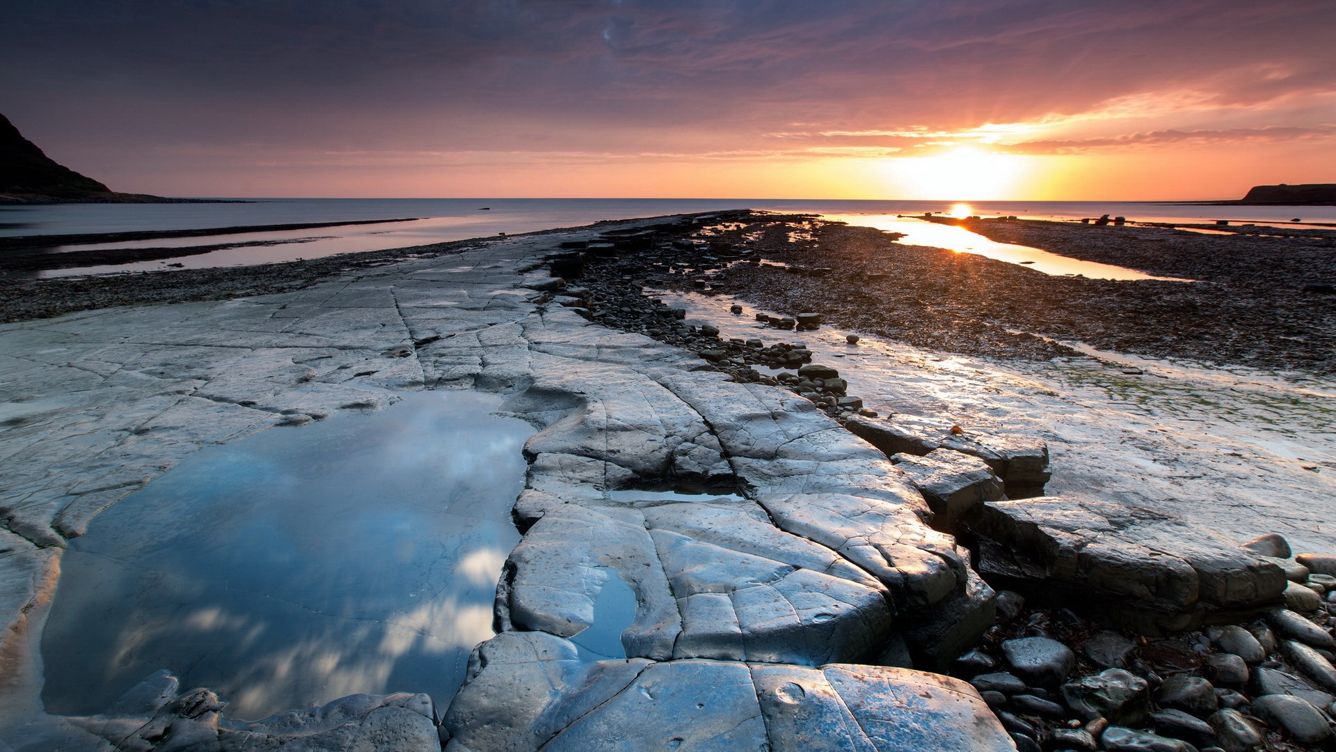 Rocky coastline at sunset with tide pools HD Wallpaper