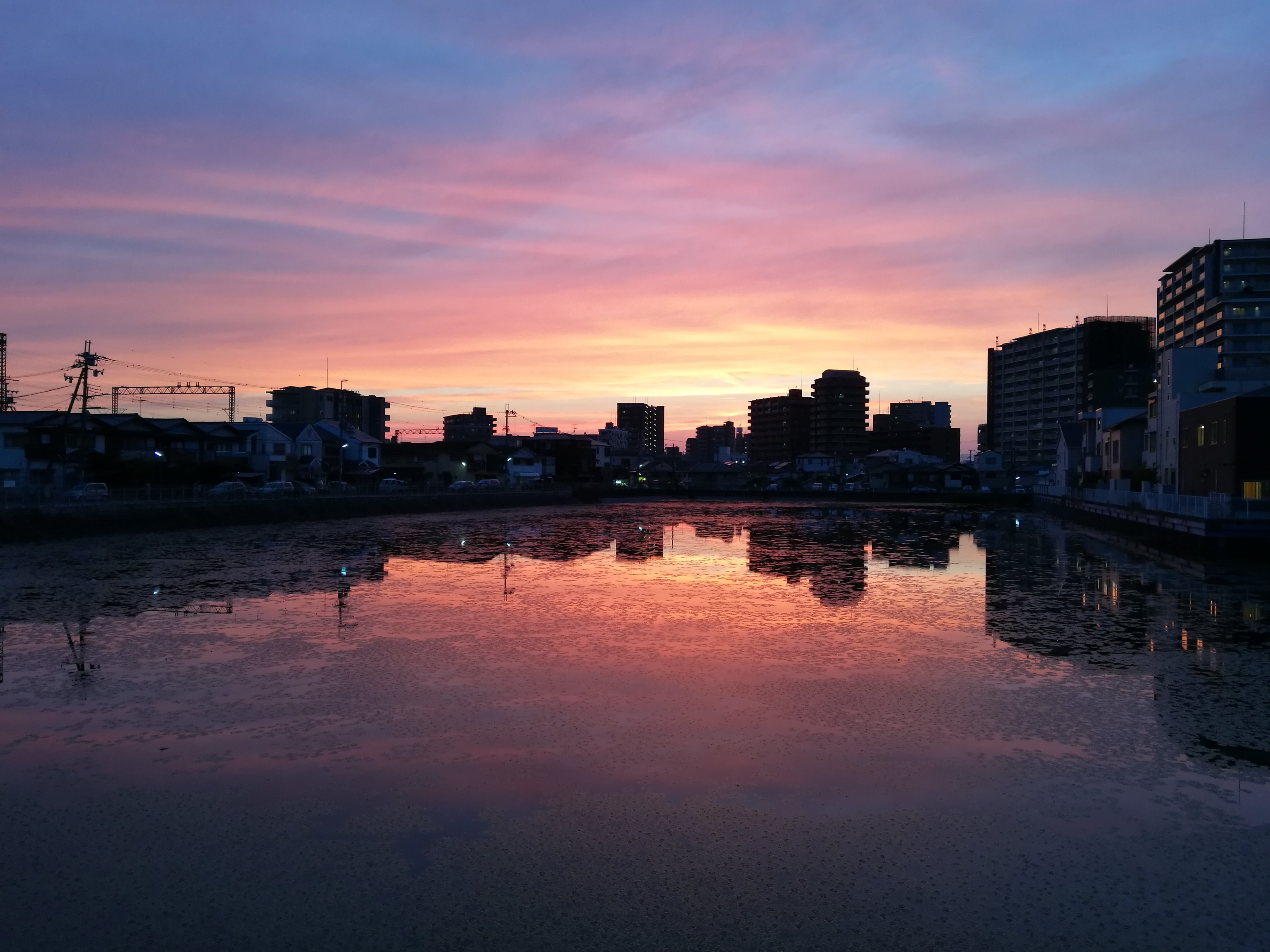 Sunset over a city skyline reflected in water HD Wallpaper