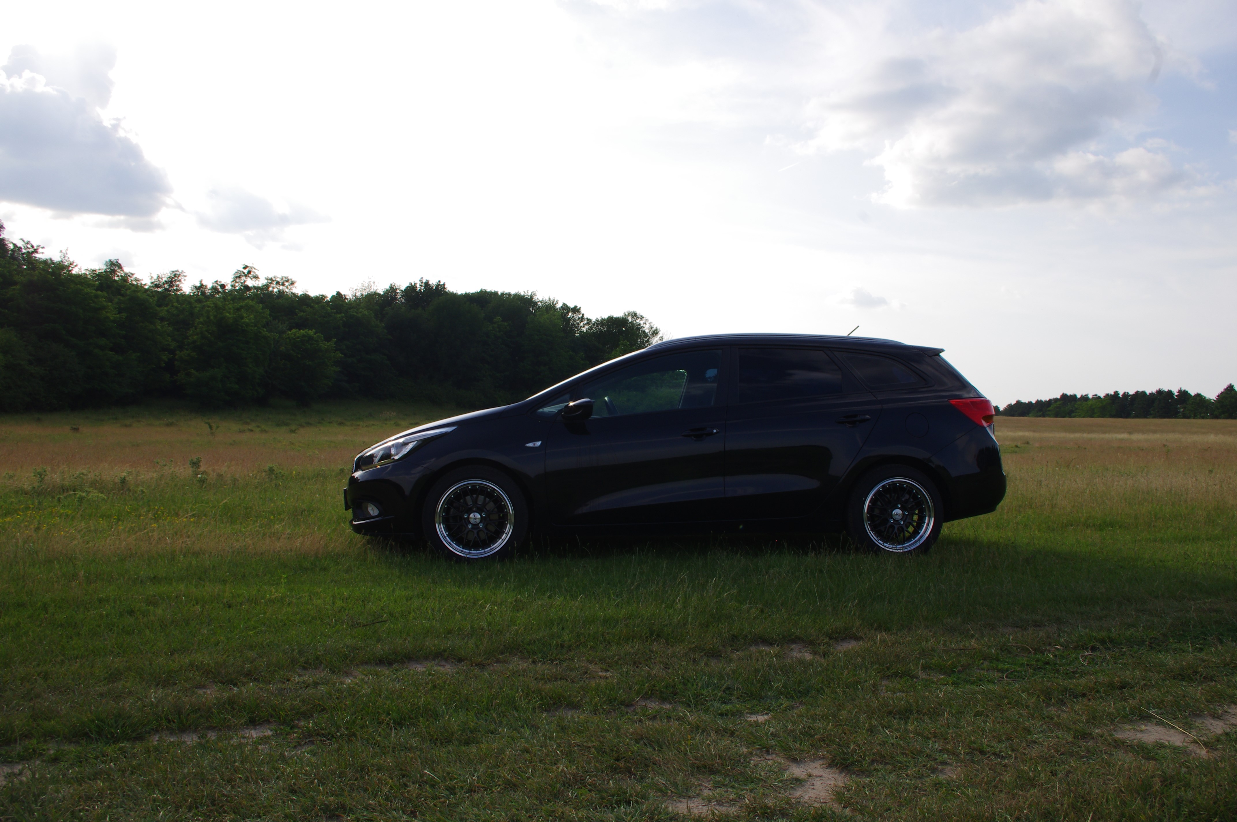 Black Kia Ceed station wagon in a field HD Wallpaper