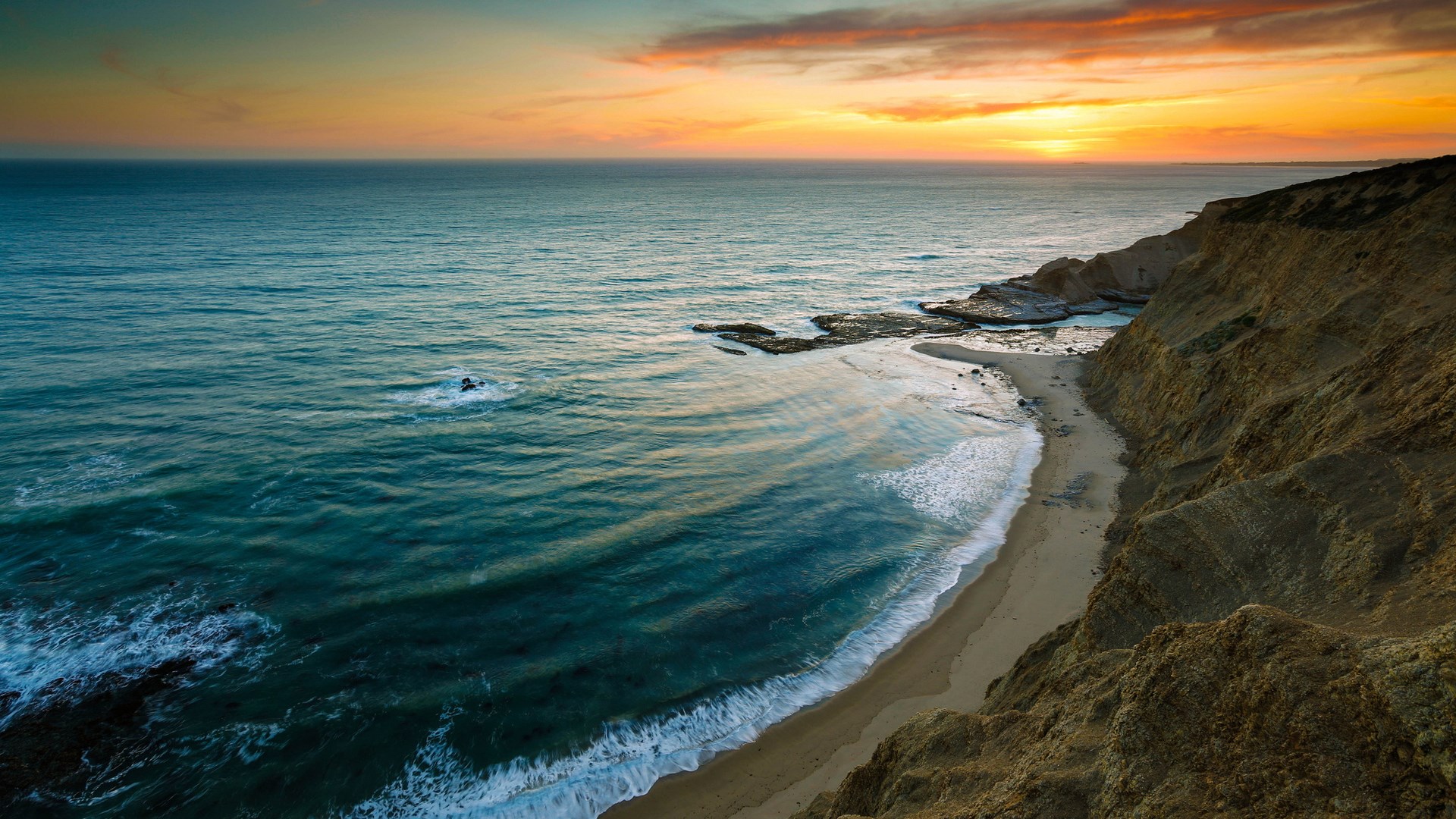 Ocean waves crash on a sandy beach at sunset HD Wallpaper