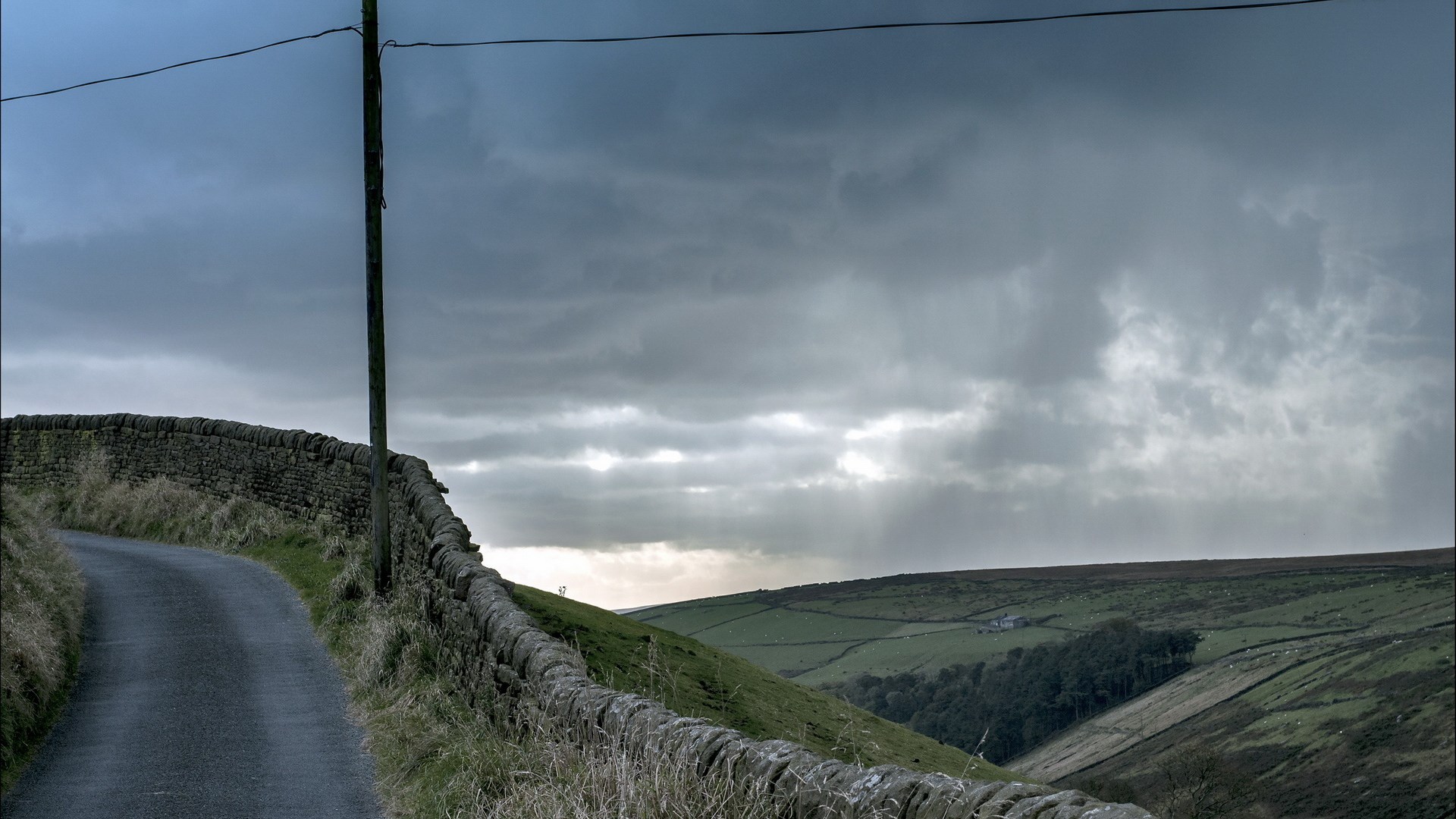 Winding country road with stone walls and stormy sky HD Wallpaper