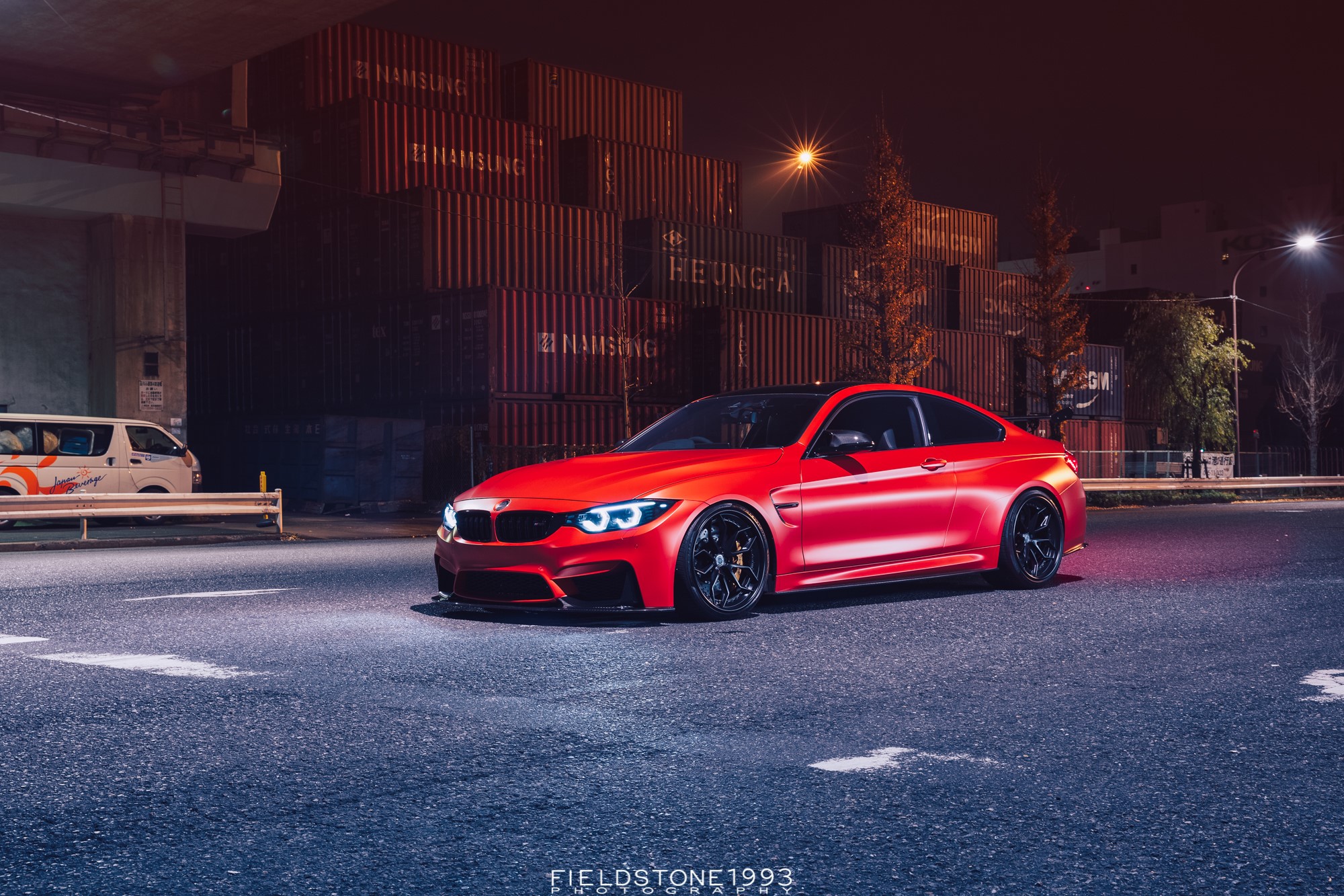 Red BMW M4 parked at night near shipping containers HD Wallpaper