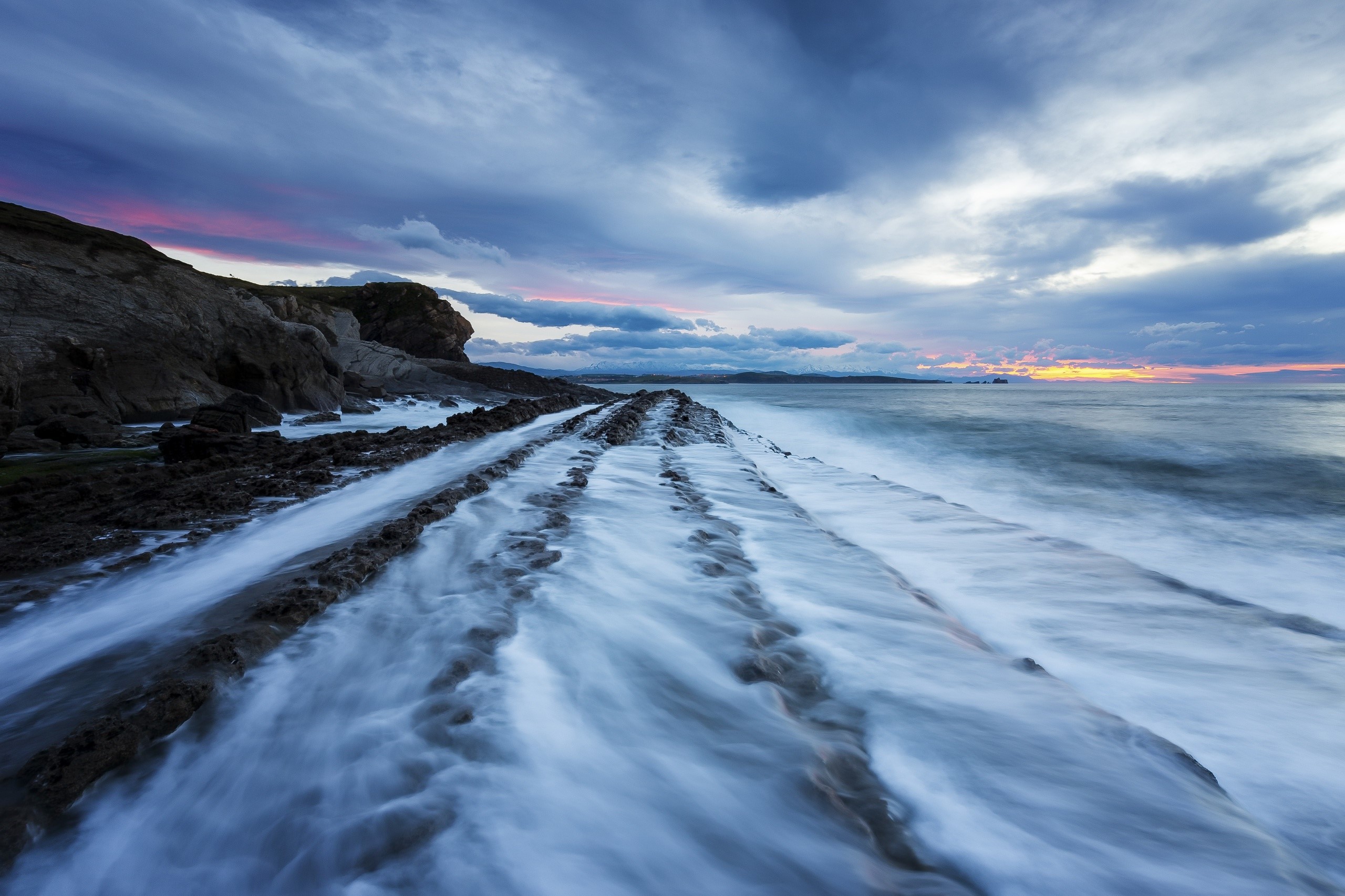 Ocean waves crashing on rocky shore at sunset HD Wallpaper