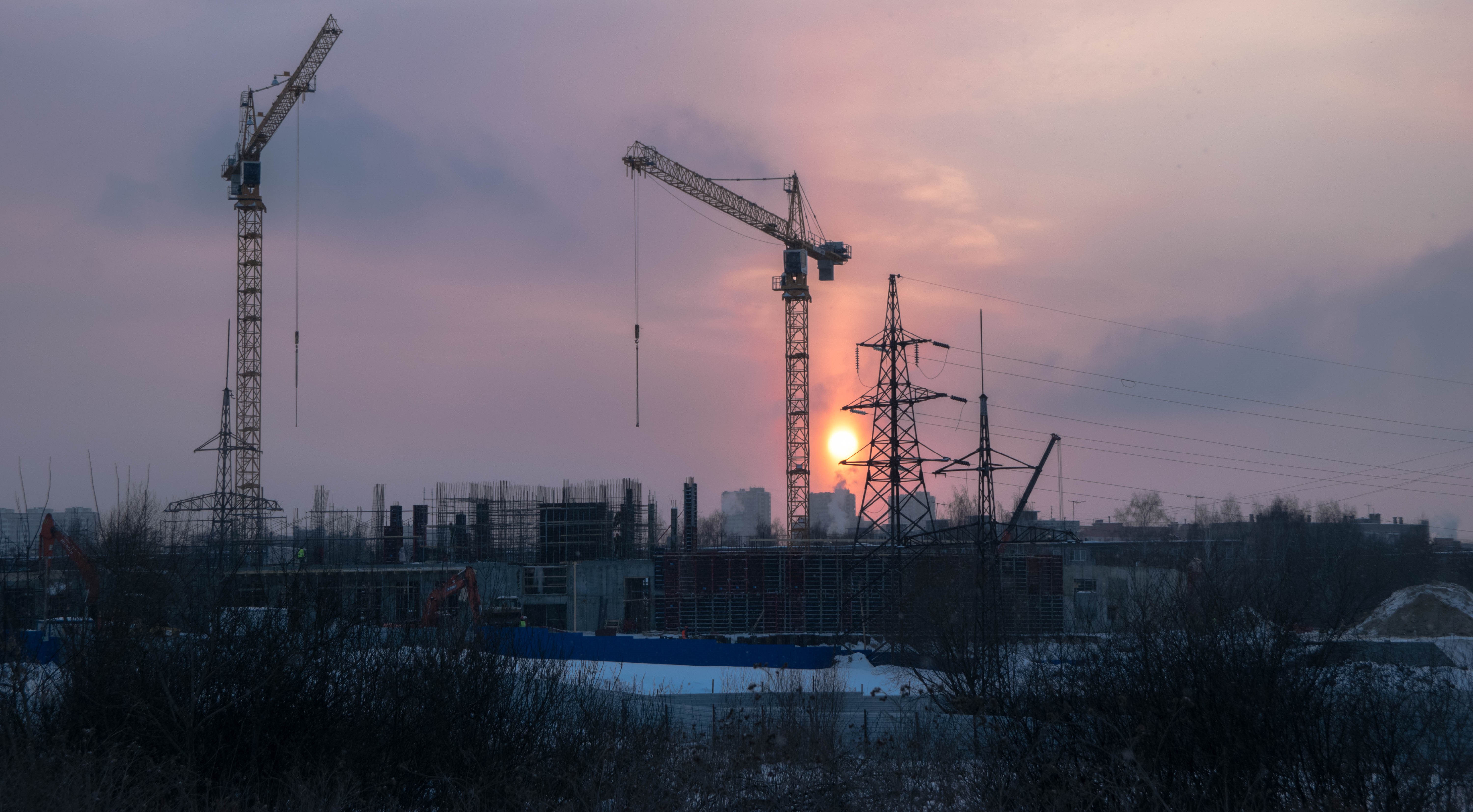 Construction cranes at sunset with power lines HD Wallpaper