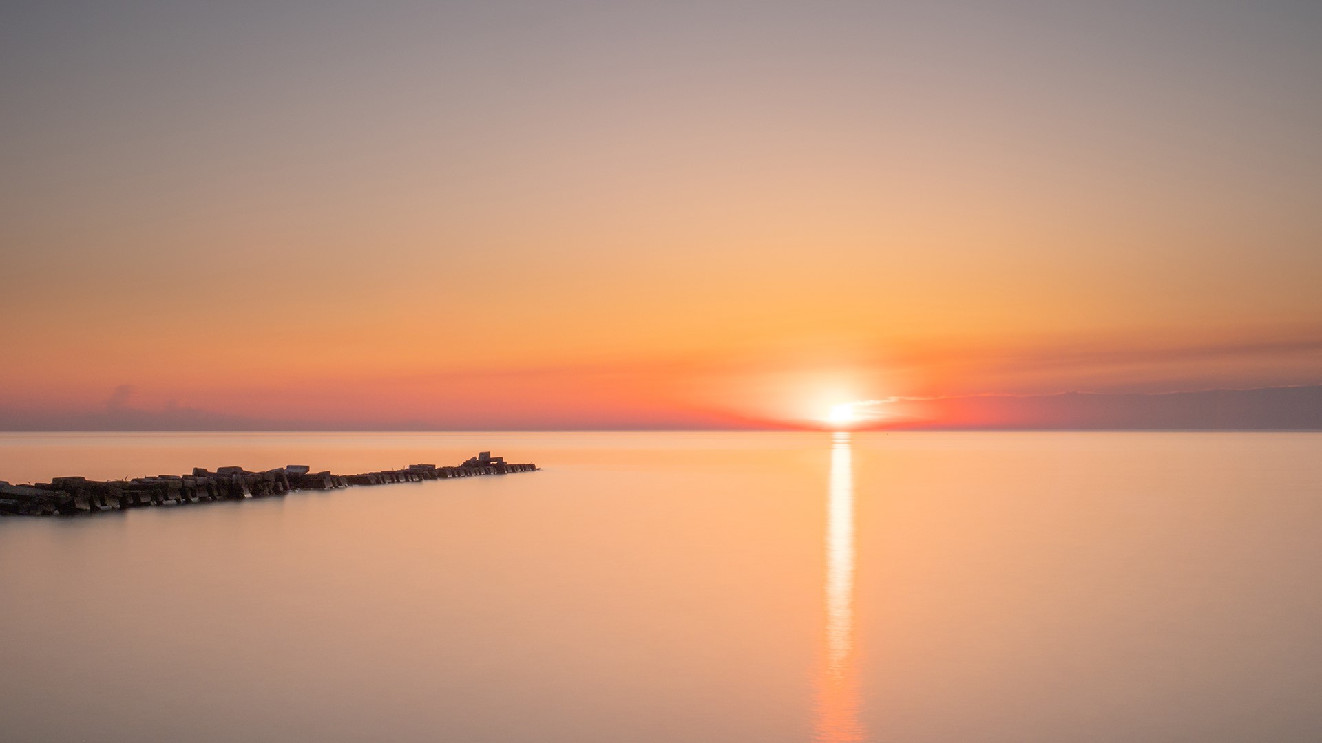 Sunset over calm water with breakwater HD Wallpaper