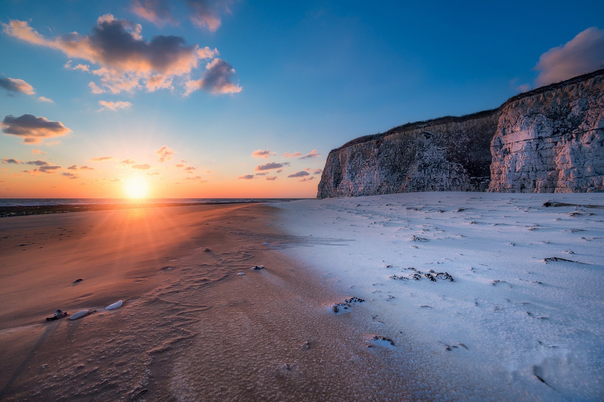 Sunset over a snowy beach with cliffs HD Wallpaper