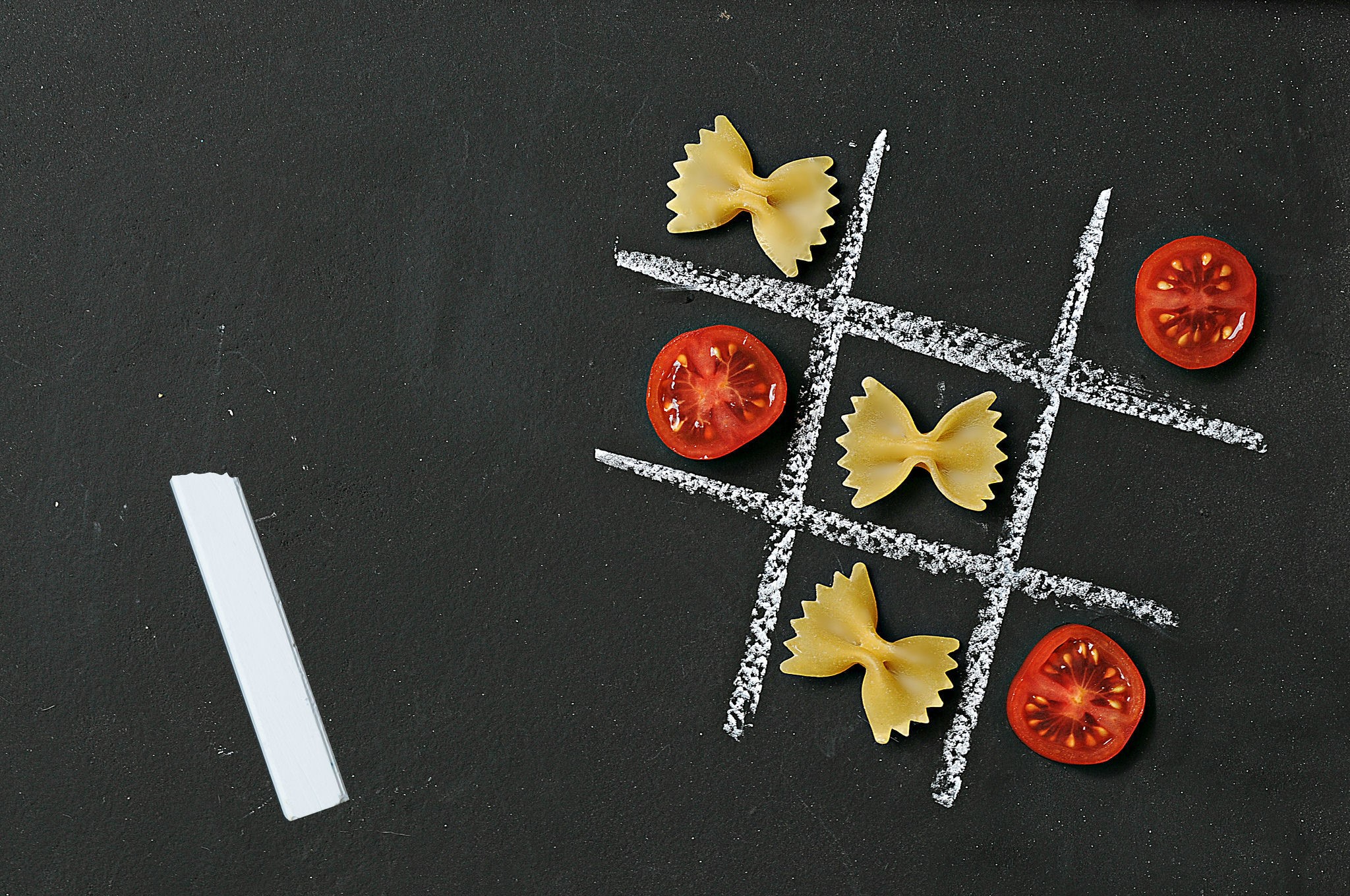 Tic-tac-toe game with pasta and tomatoes on chalkboard HD Wallpaper