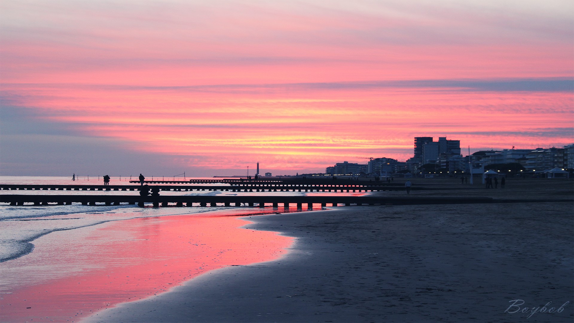 Sunset over a beach with a pier and city skyline HD Wallpaper