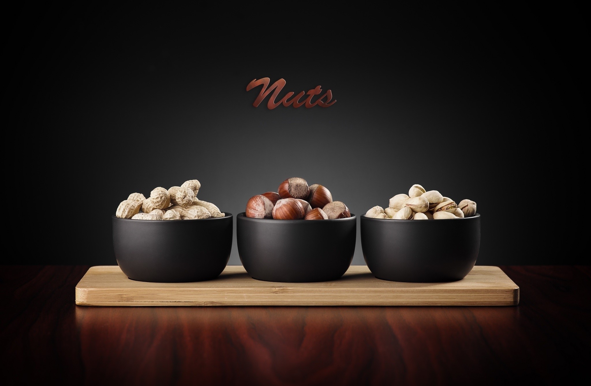 Three bowls of nuts on a wooden board HD Wallpaper