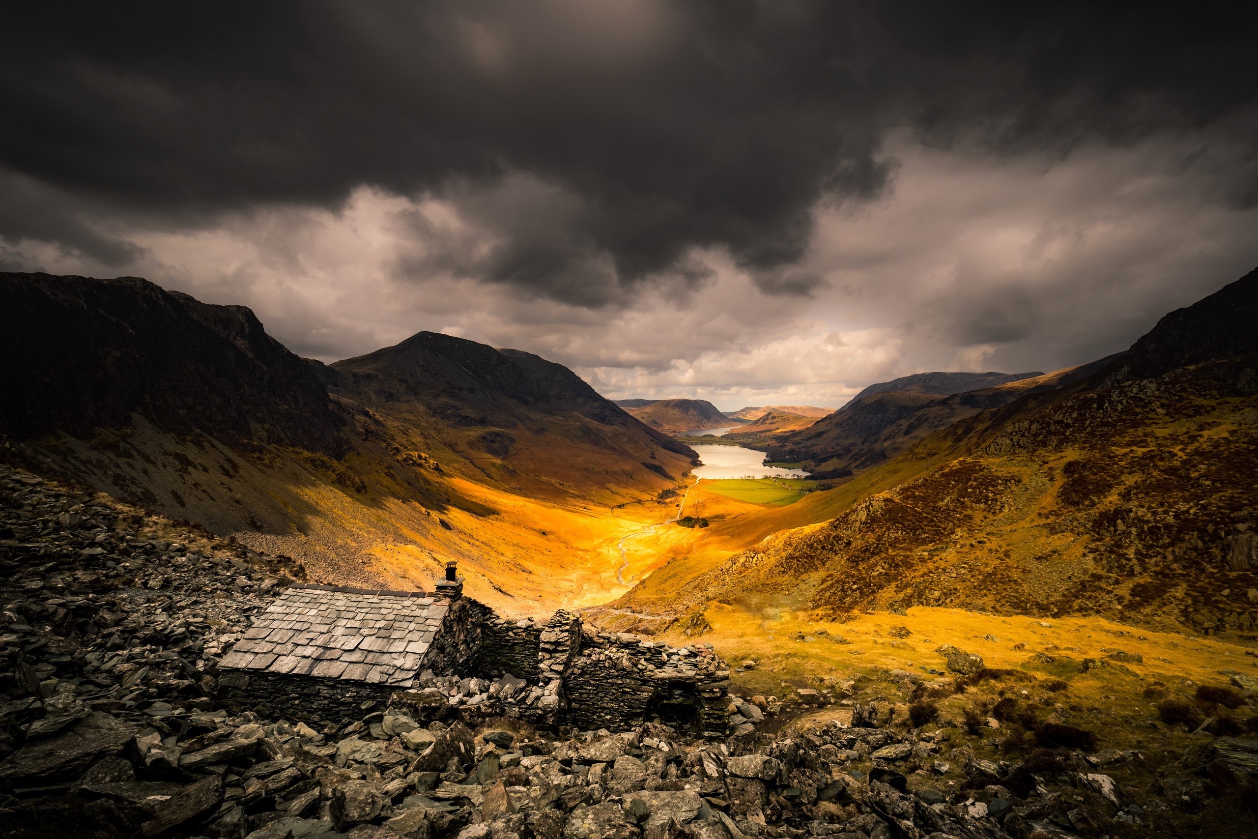 Stone cottage in a valley with a lake and mountains HD Wallpaper