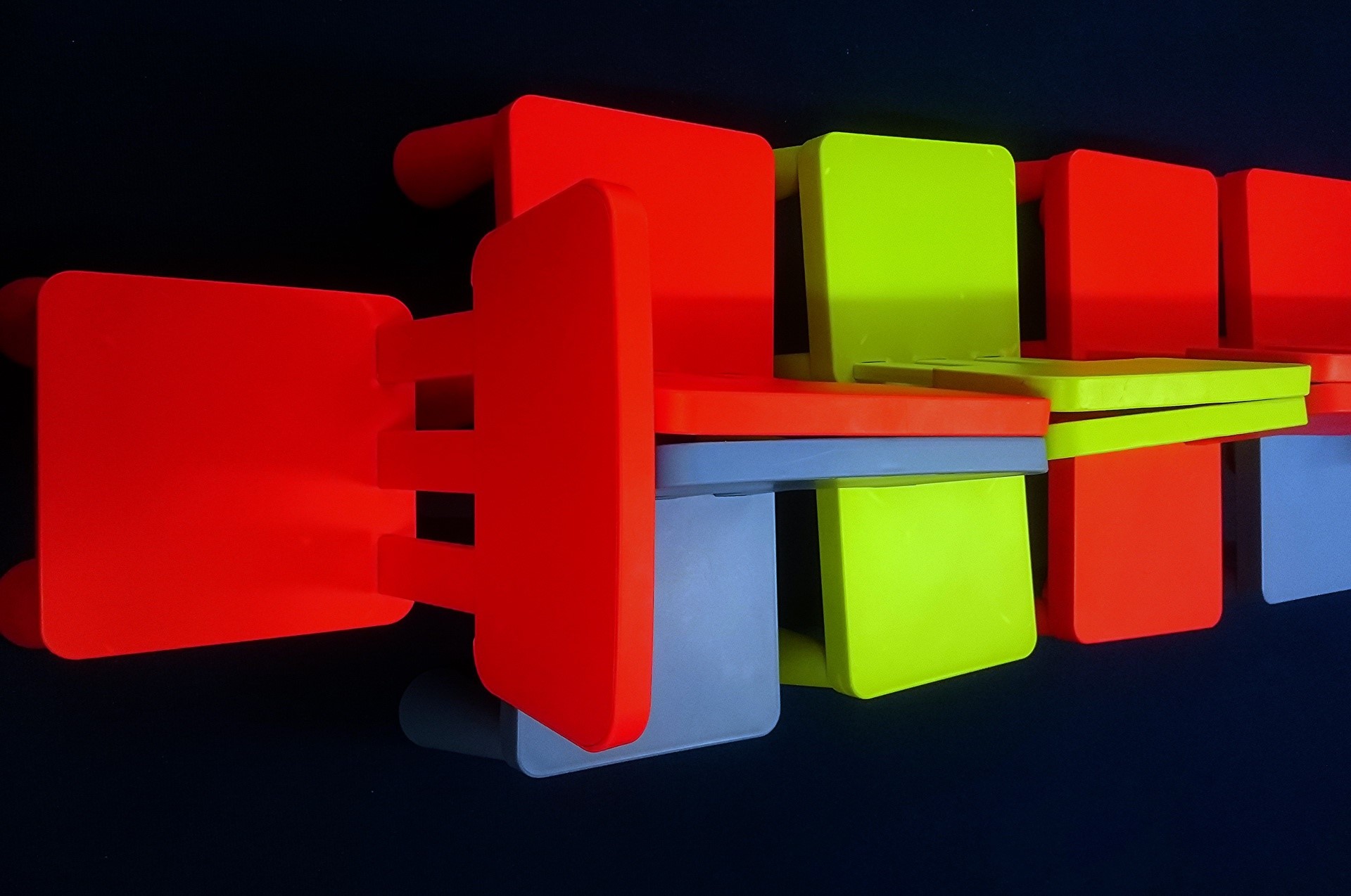 Stack of colorful chairs on a black background HD Wallpaper