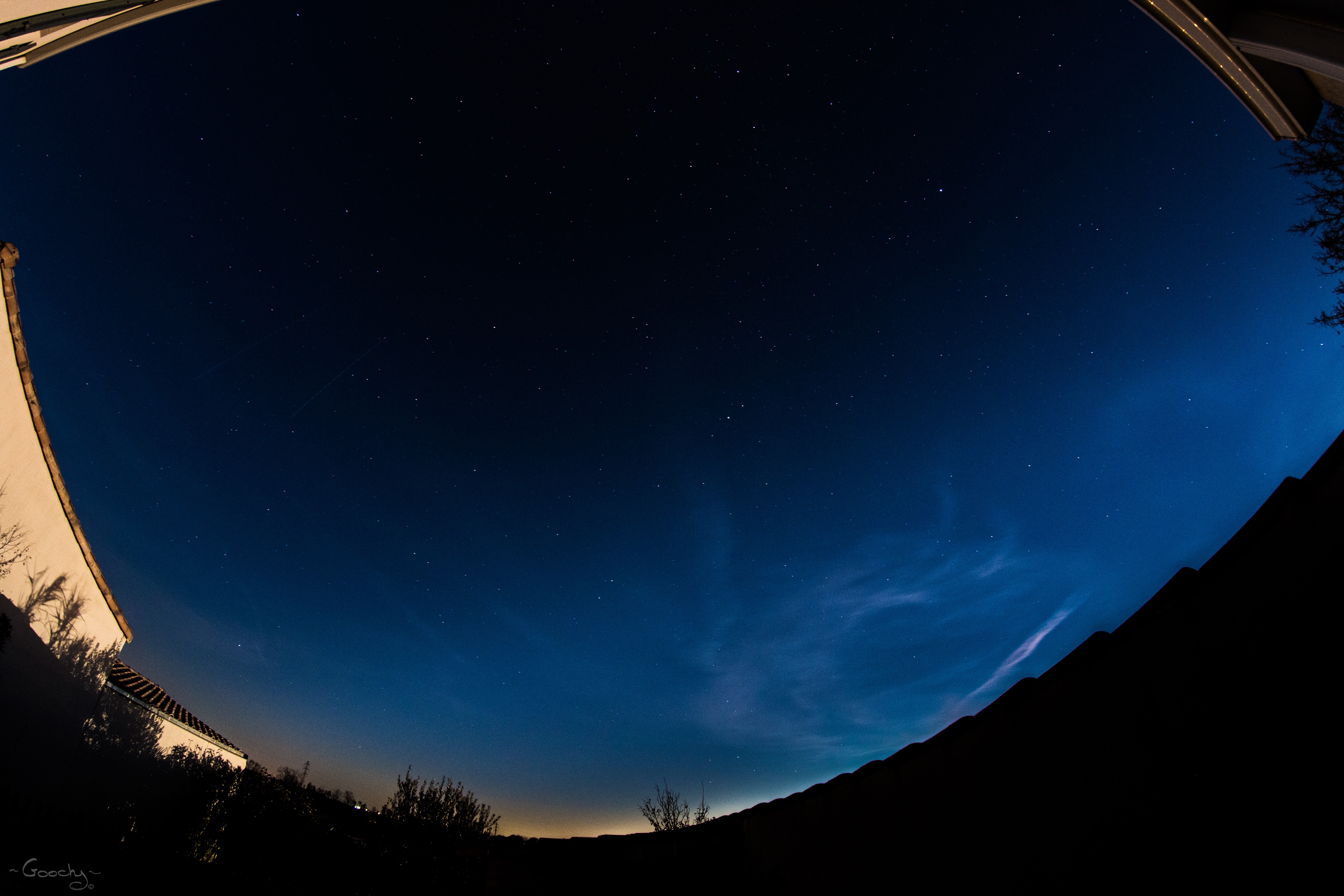 Night sky with stars and clouds over a silhouette of buildings and trees HD Wallpaper