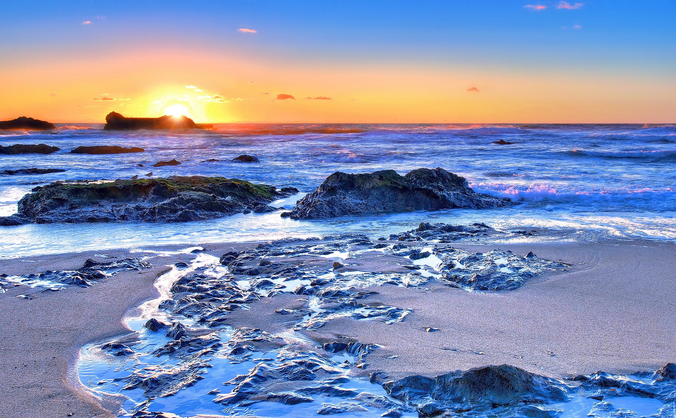 Sunset over a rocky beach with waves HD Wallpaper