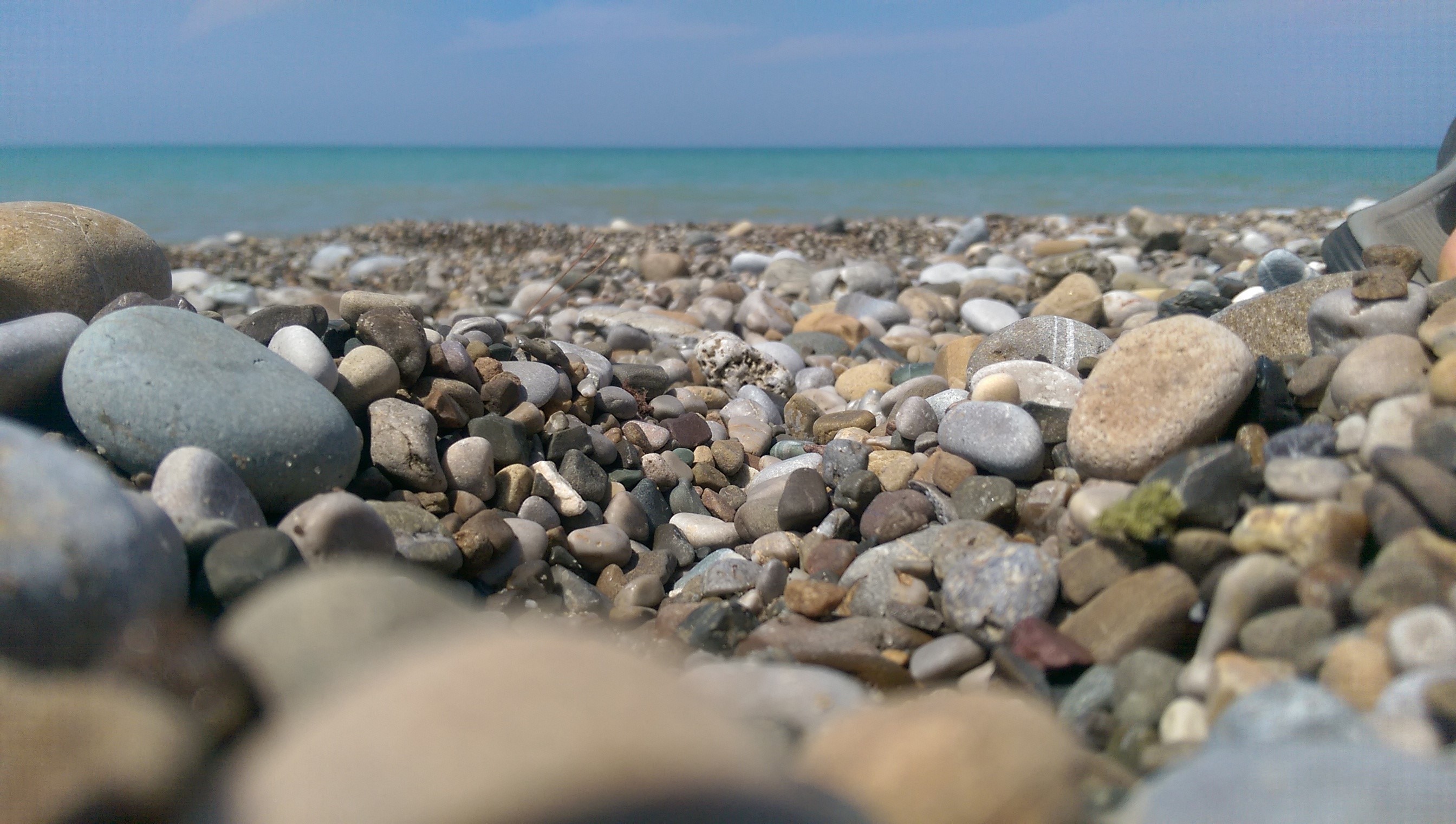 Pebble beach with turquoise sea and horizon HD Wallpaper
