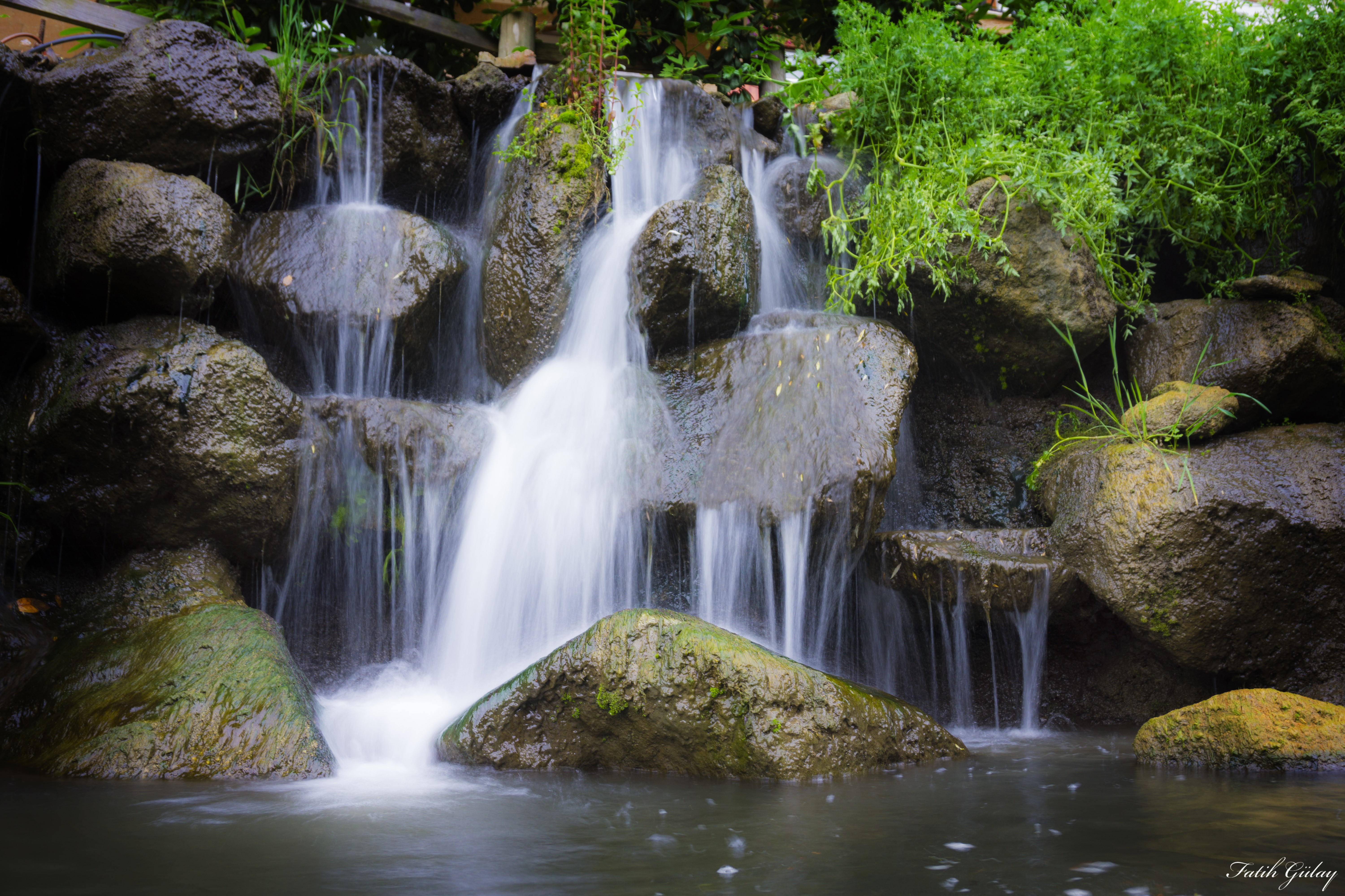 Waterfall cascading over rocks with plants HD Wallpaper