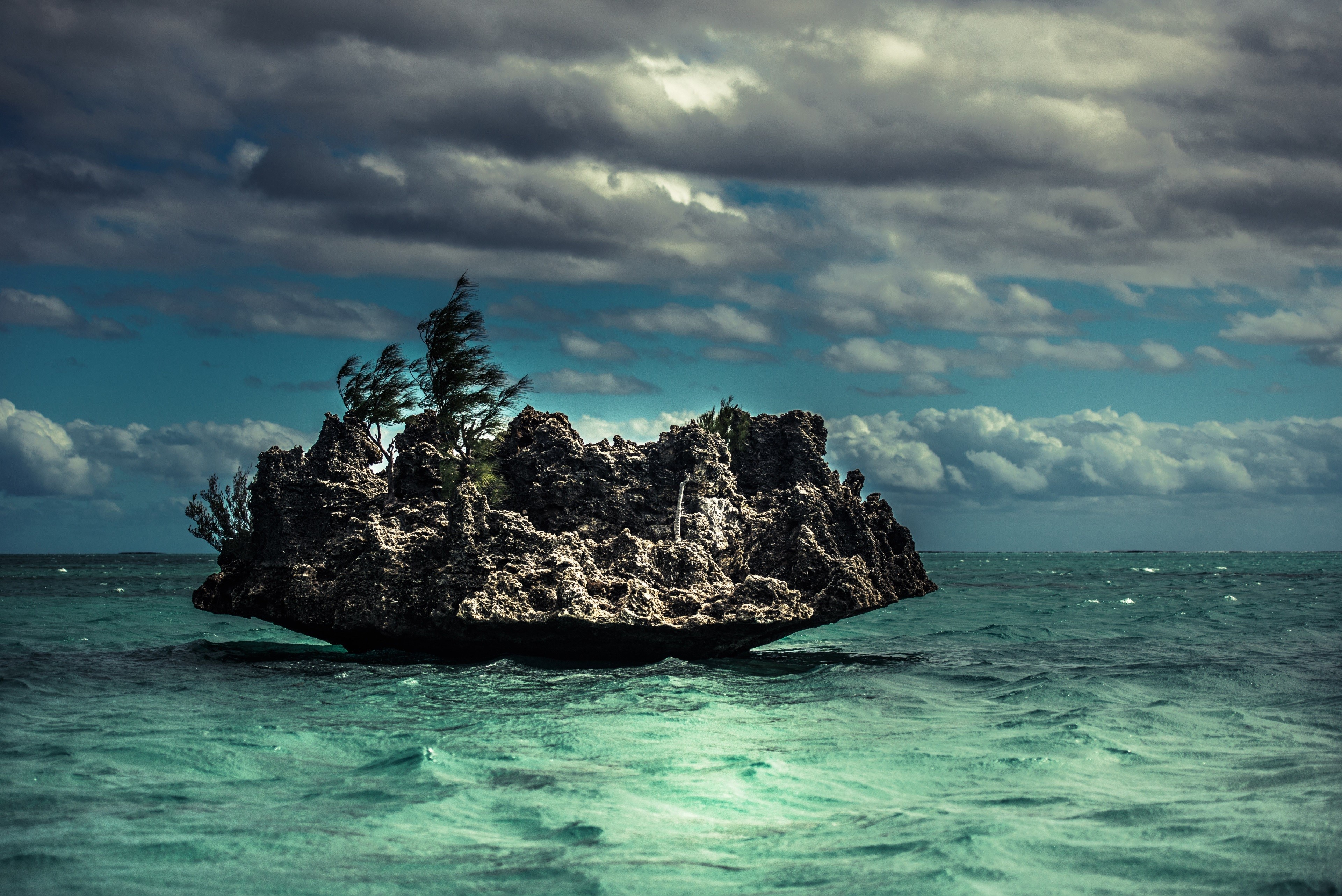 Rock island with trees in the sea under clouds HD Wallpaper