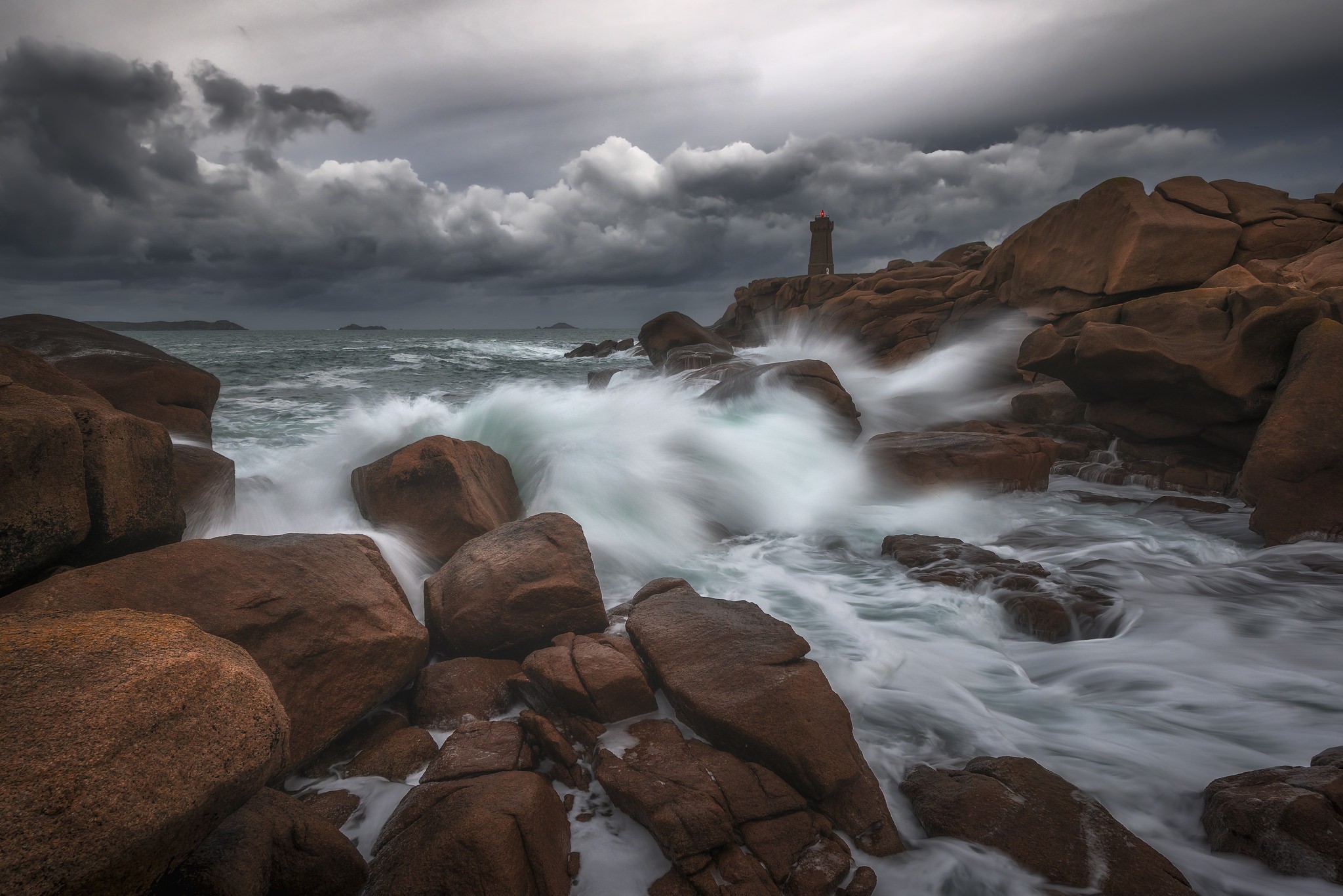 Lighthouse on rocky coast with crashing waves HD Wallpaper