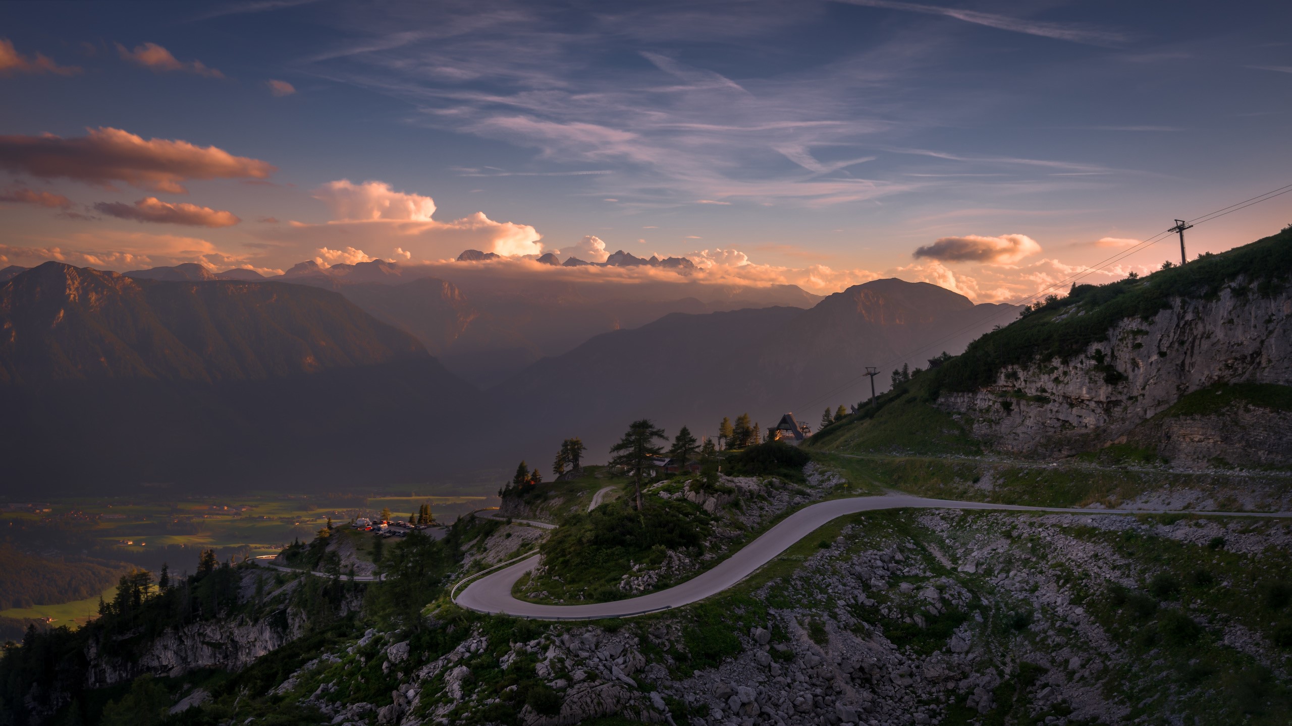 Winding mountain road at sunset with distant peaks HD Wallpaper