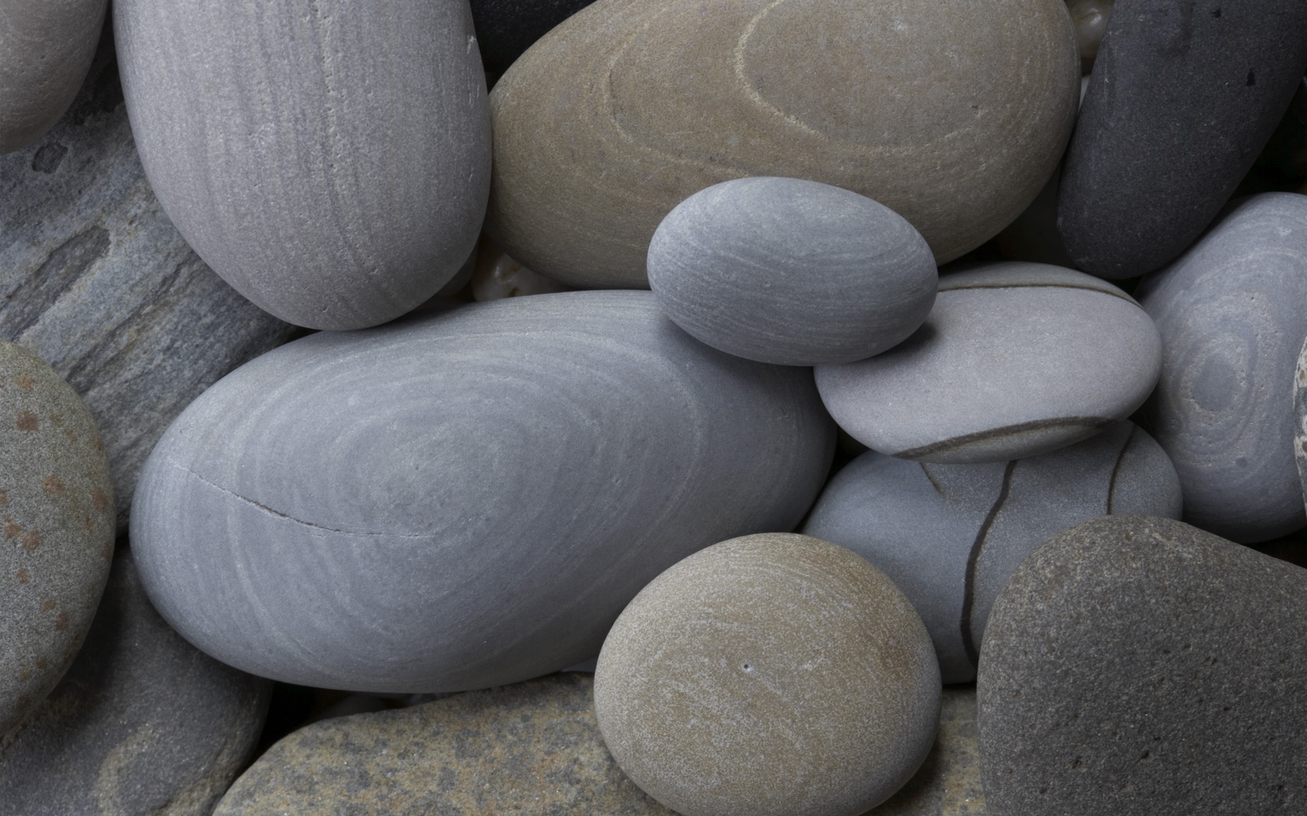 Close-up of smooth, rounded stones with varied textures and colors HD Wallpaper