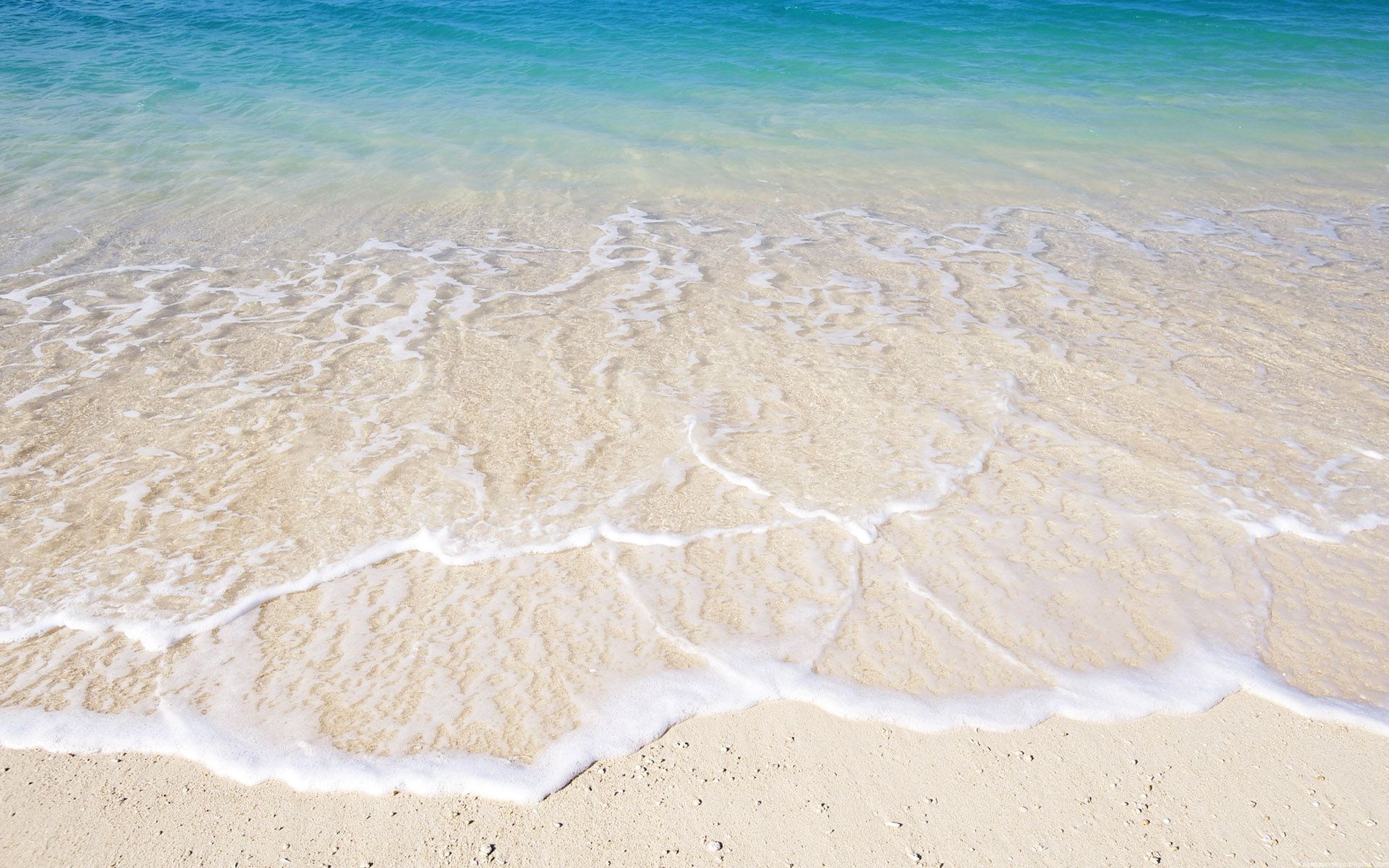 Ocean waves washing onto a sandy beach HD Wallpaper