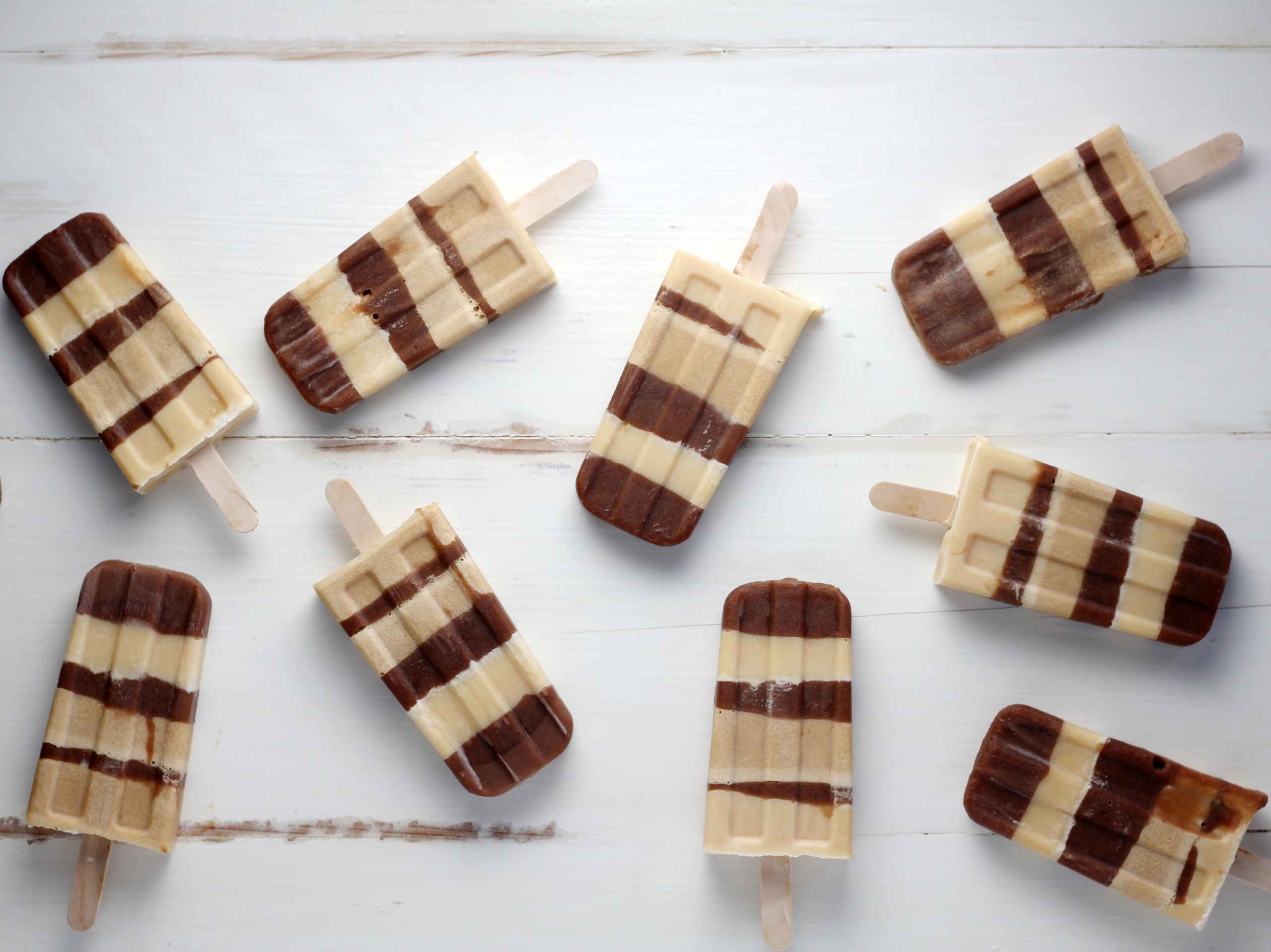 Chocolate and vanilla striped popsicles on white wood HD Wallpaper