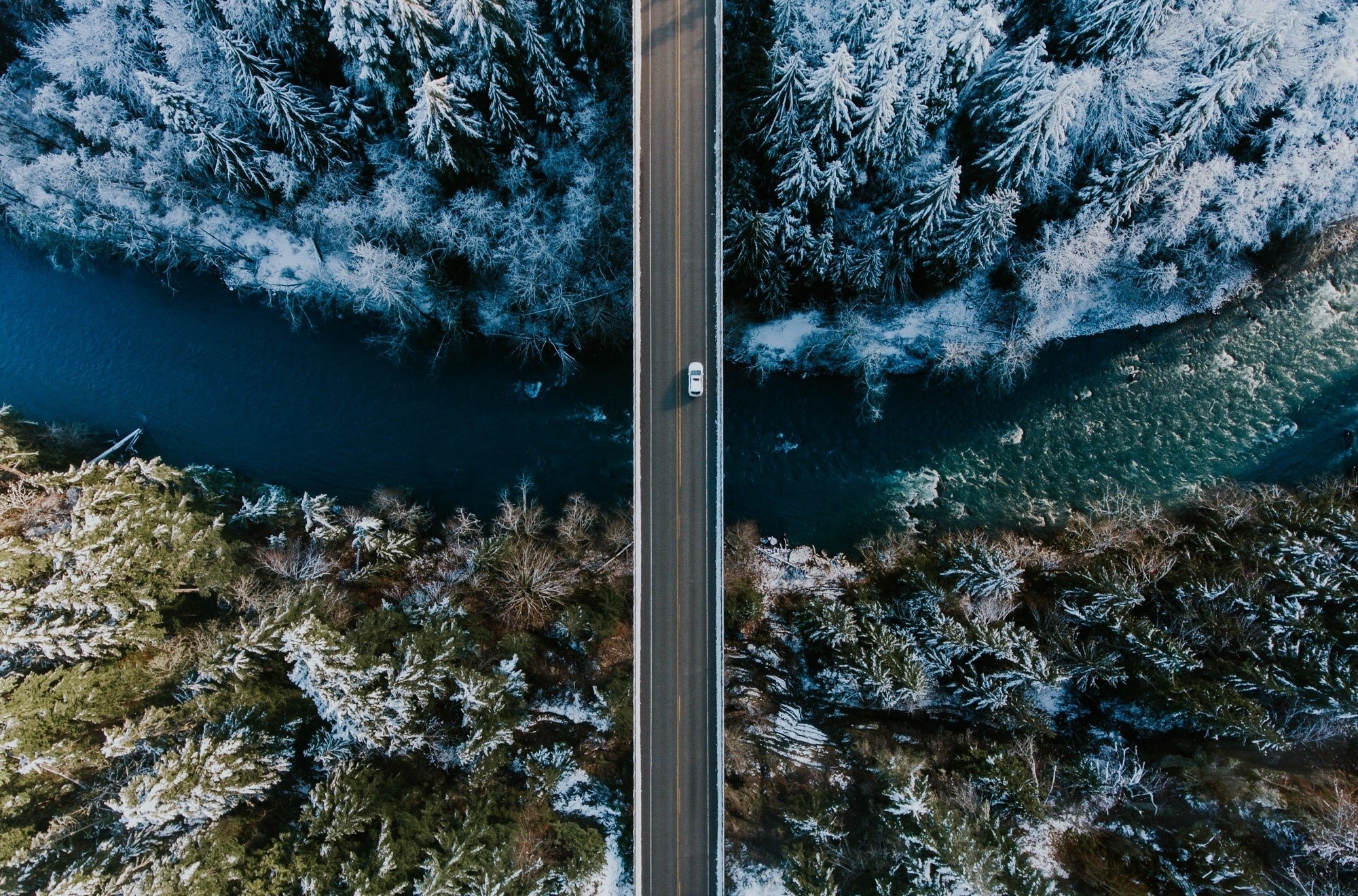 Aerial view of a car on a bridge over a river in winter HD Wallpaper