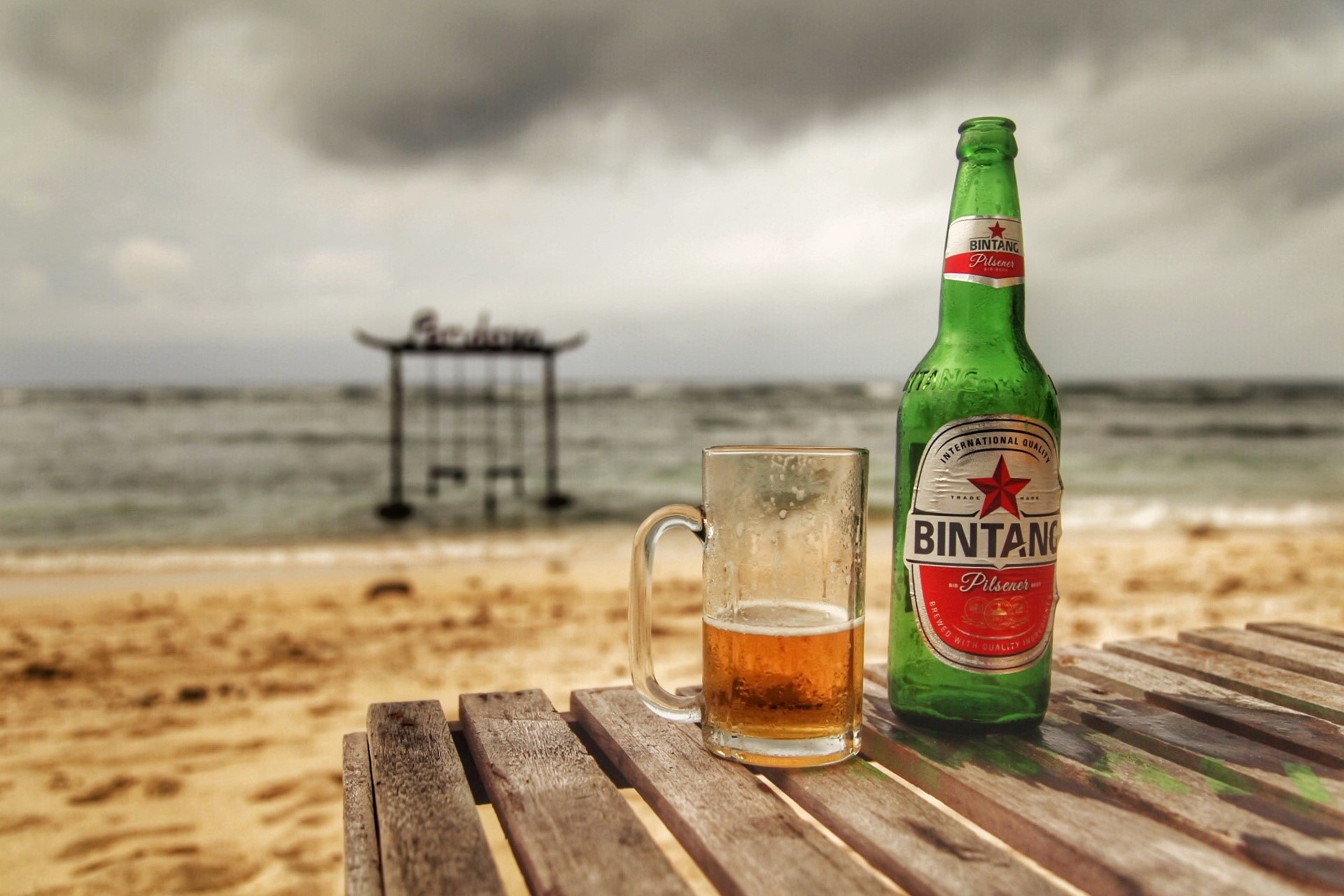 Bintang beer bottle and glass on a table at the beach HD Wallpaper
