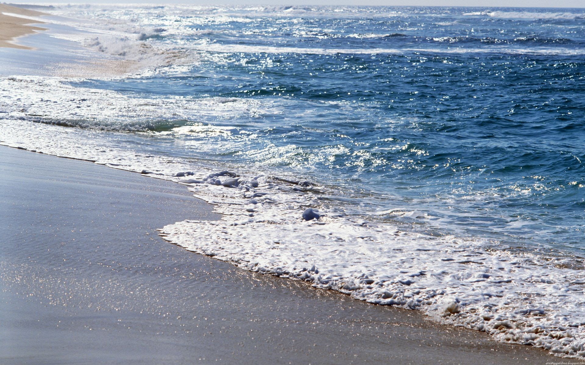 Ocean waves washing onto a sandy beach HD Wallpaper