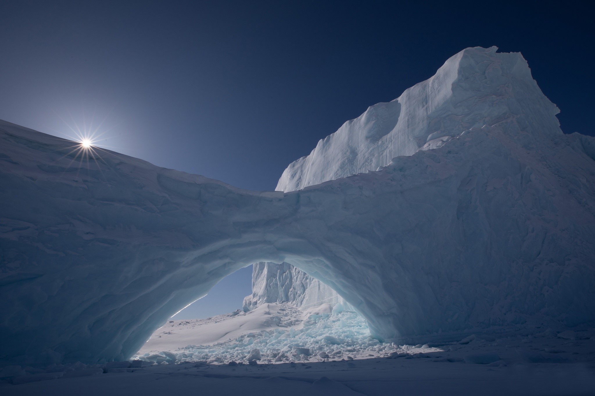 Sunburst over an icy archway in Antarctica HD Wallpaper