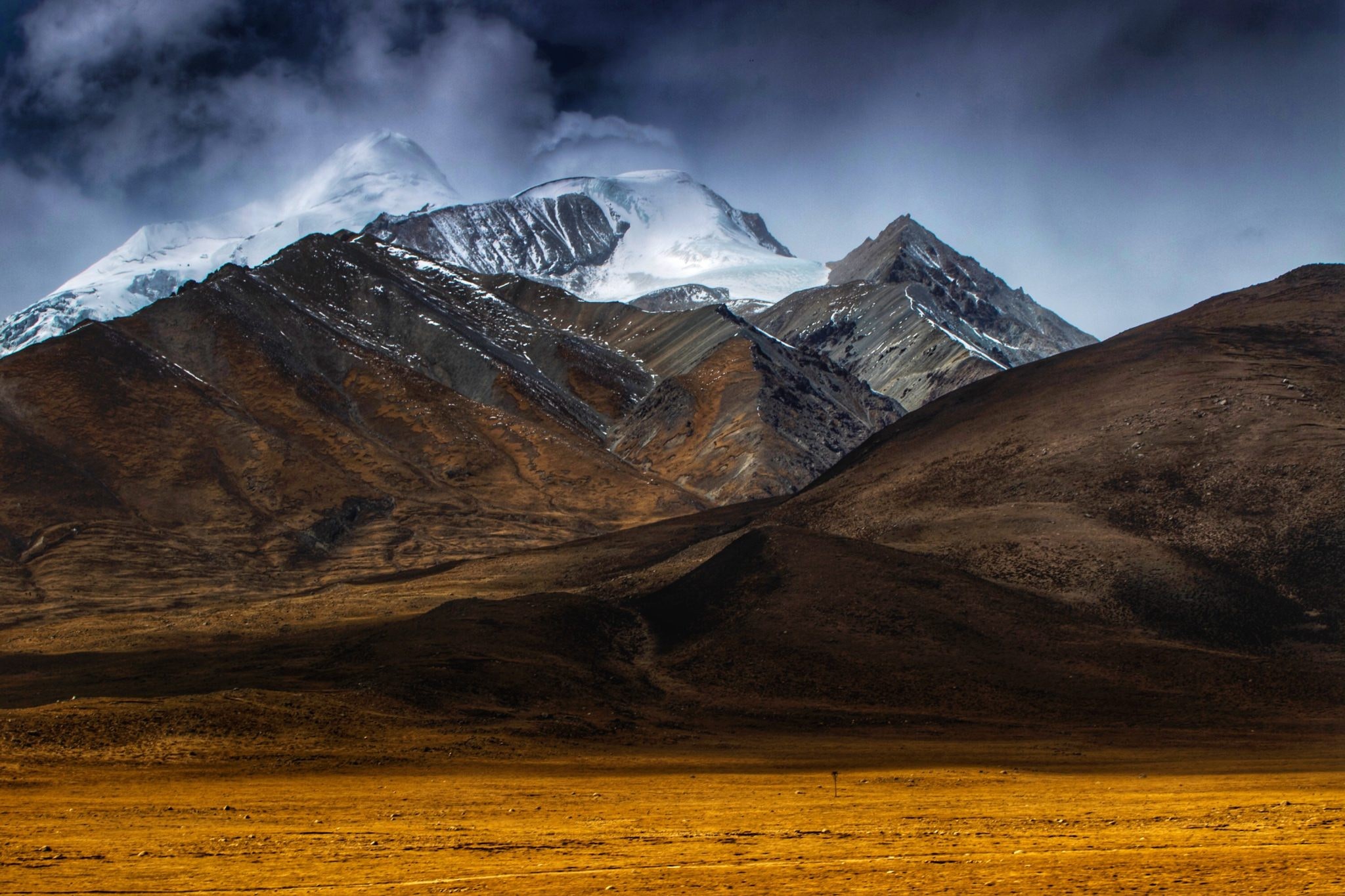 Snow-capped mountains under a dark sky HD Wallpaper
