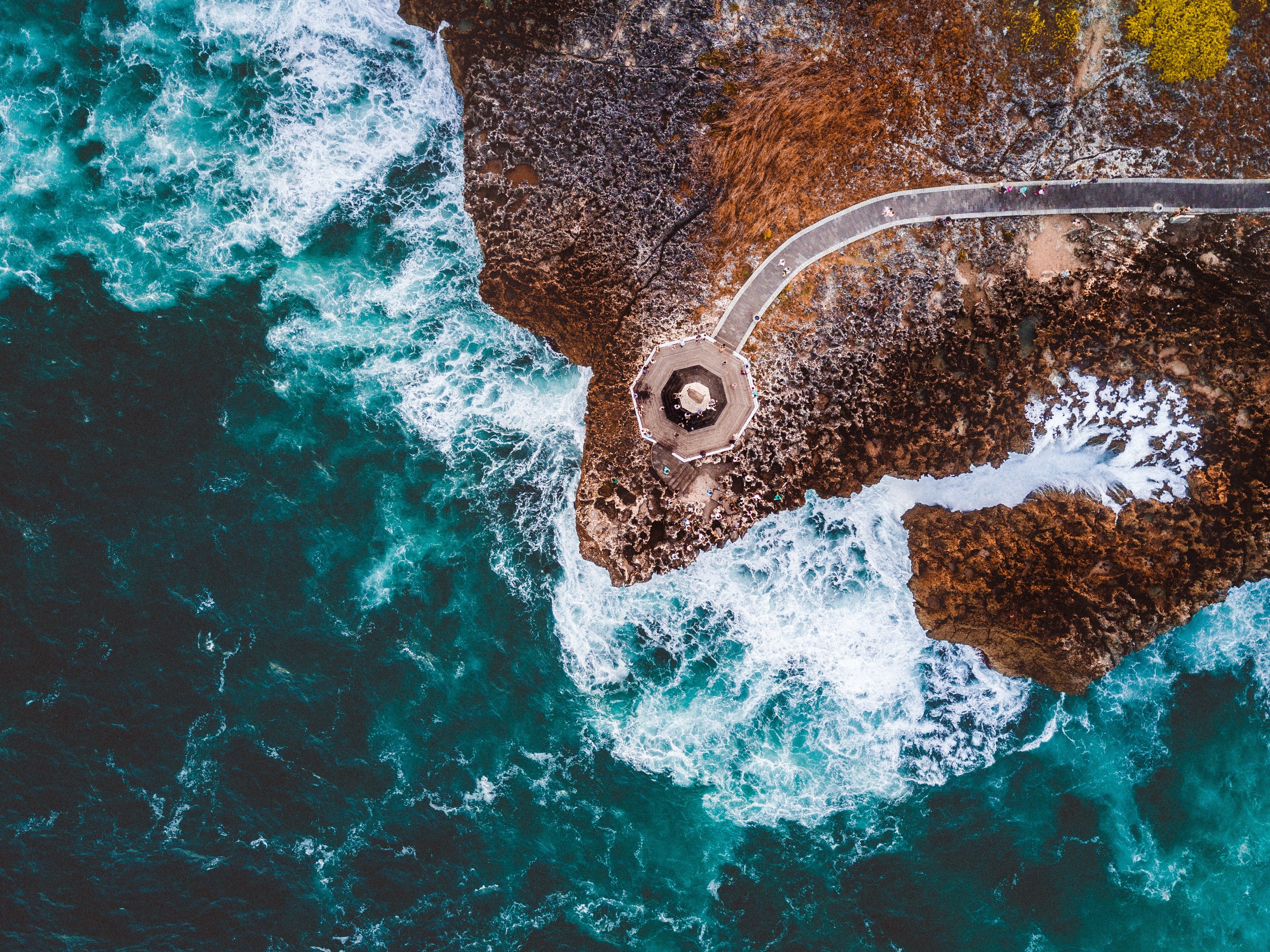 Aerial view of a coastal path and ocean waves HD Wallpaper