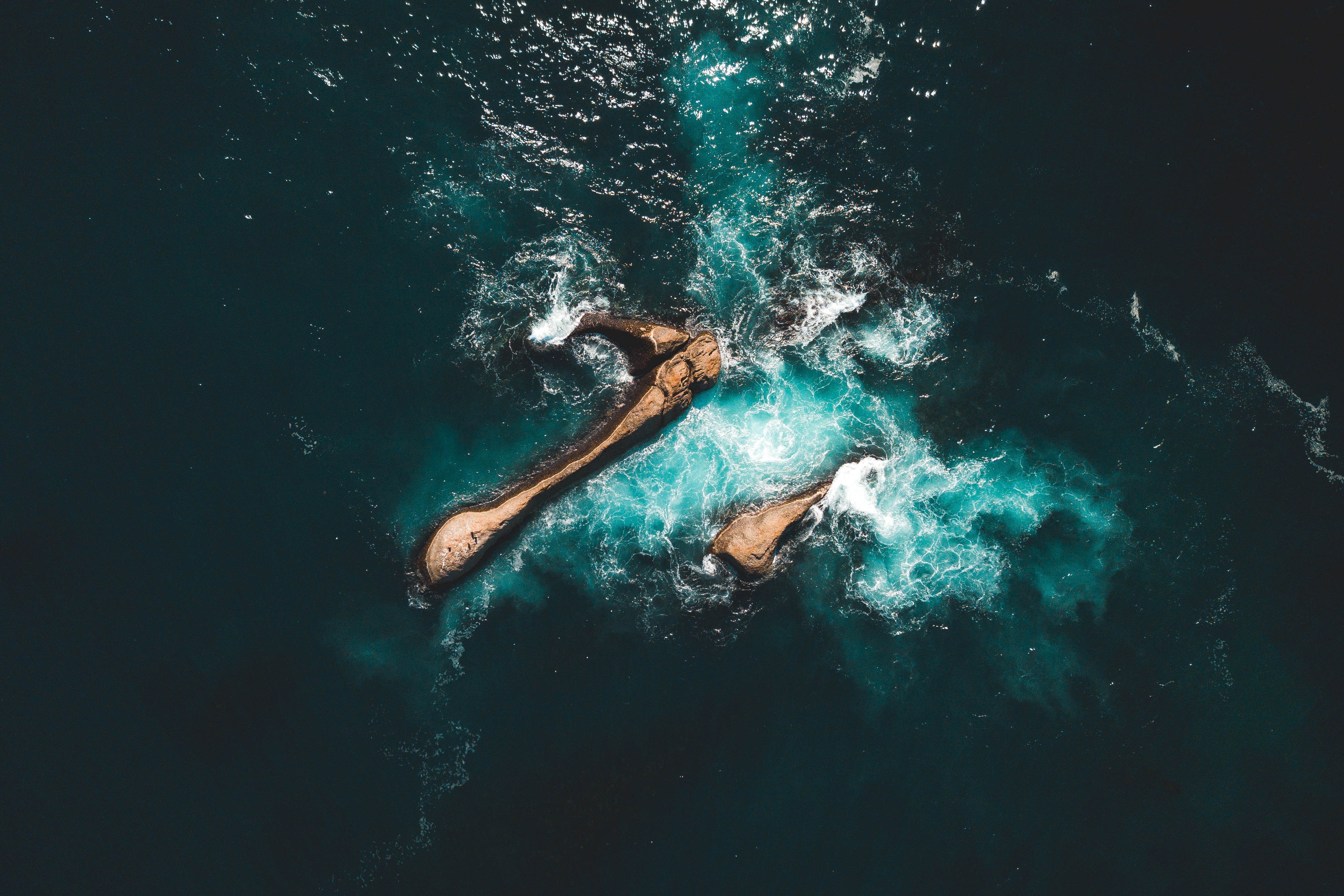 Aerial view of rocks in turquoise sea HD Wallpaper