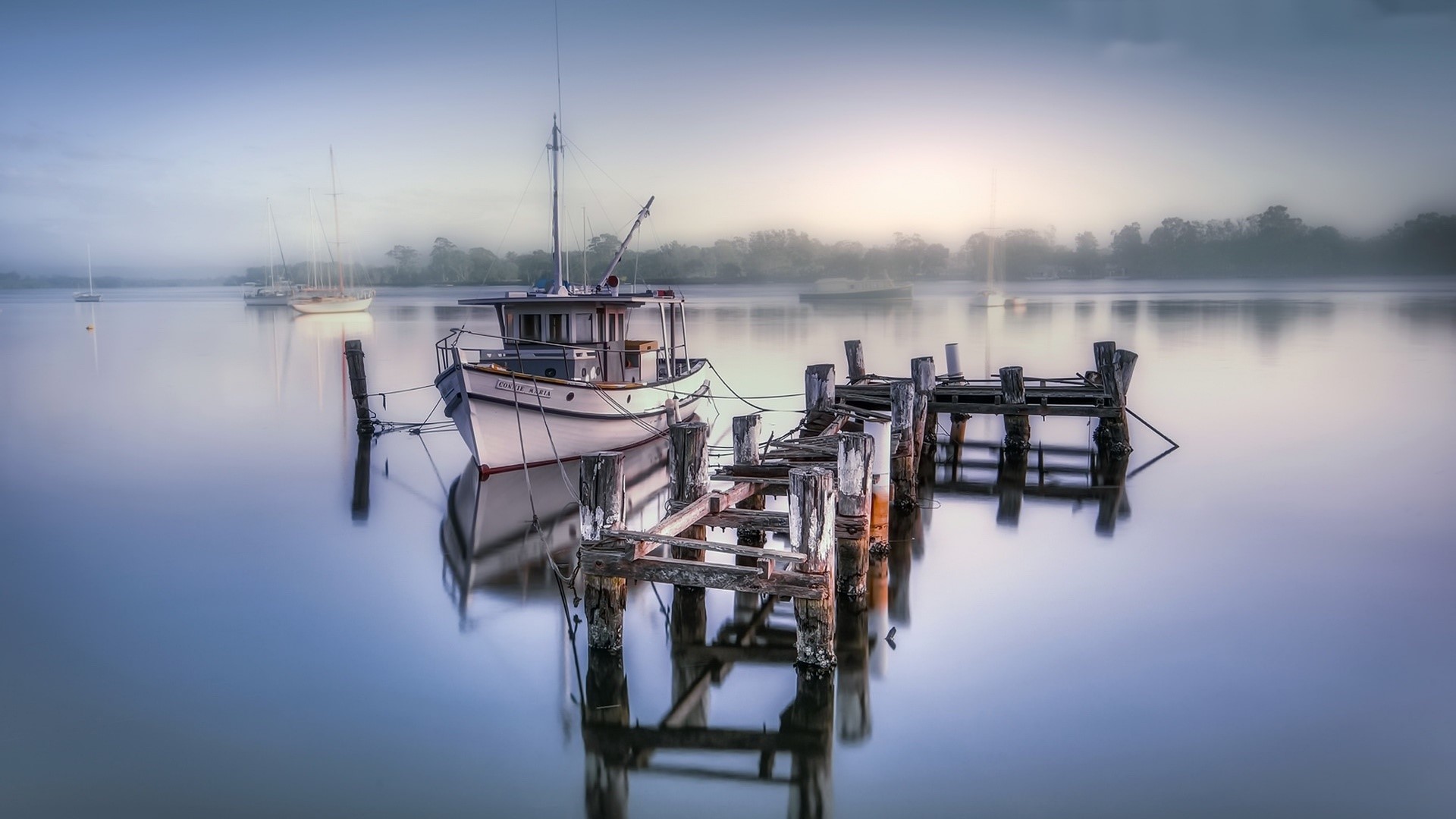 Boat docked at a weathered pier on a misty lake HD Wallpaper