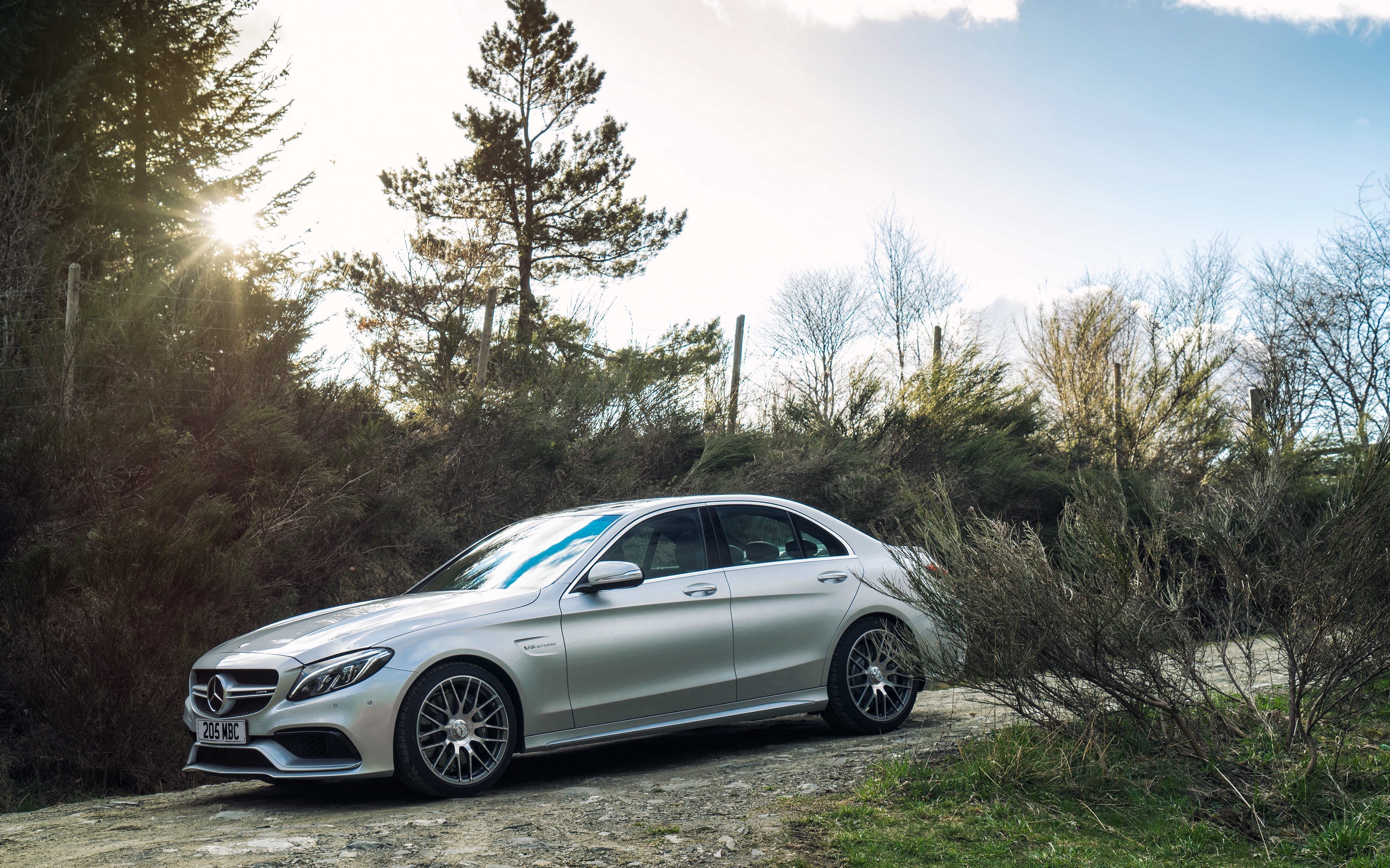 Silver Mercedes Benz C63 AMG Sedan on a Dirt Road HD Wallpaper