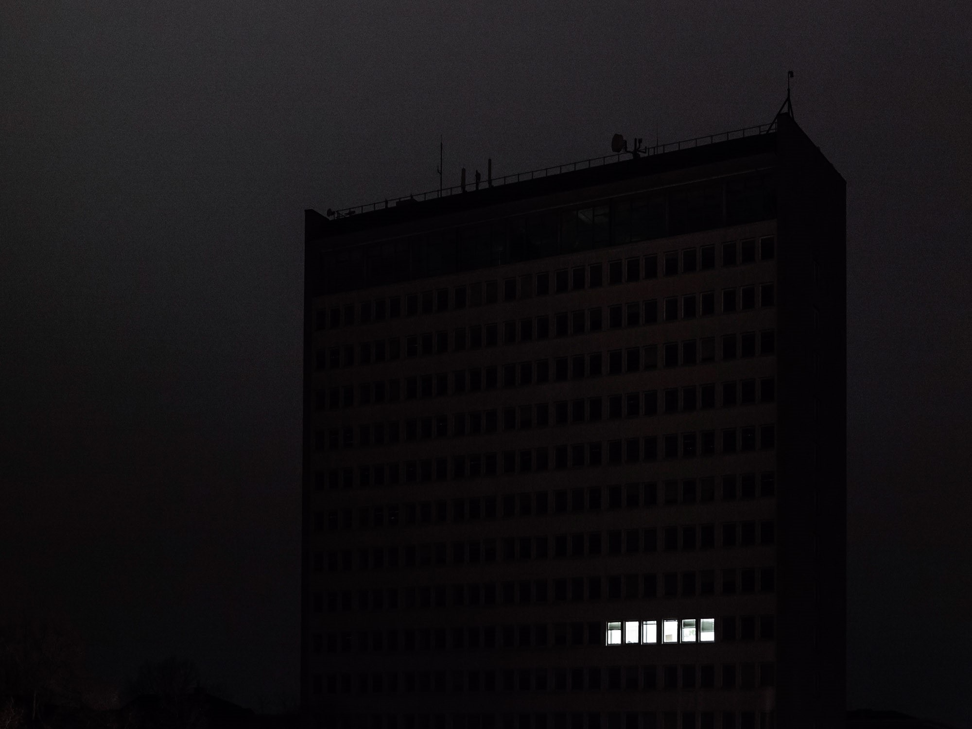 Dark building at night with lit windows HD Wallpaper