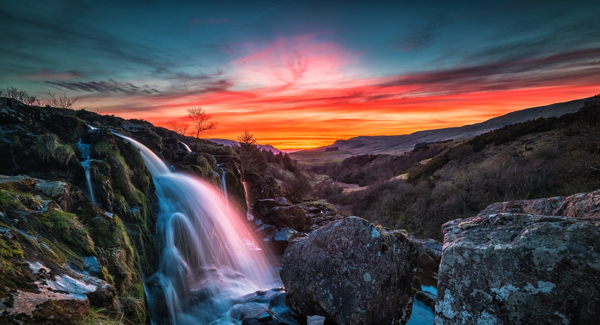 Waterfall flowing over rocks at sunset HD Wallpaper