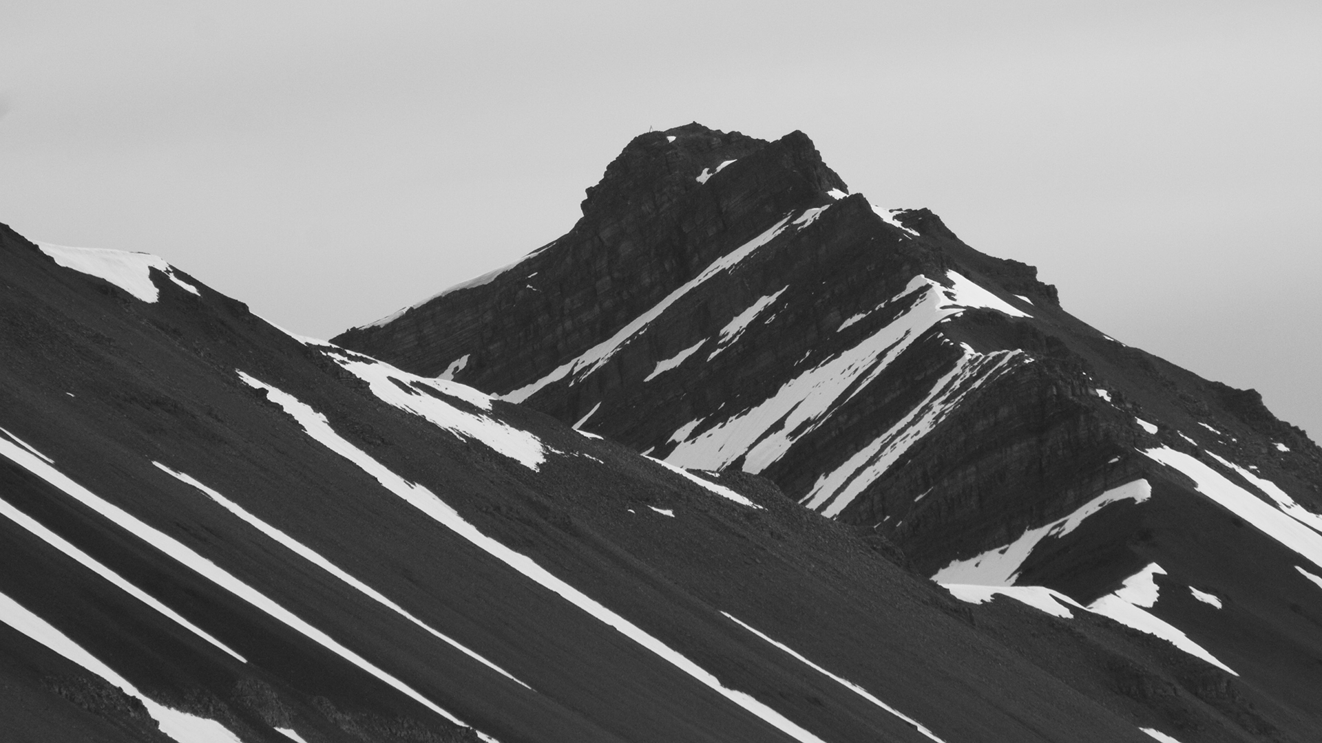 Monochrome image of snowy mountain peaks under an overcast sky HD Wallpaper