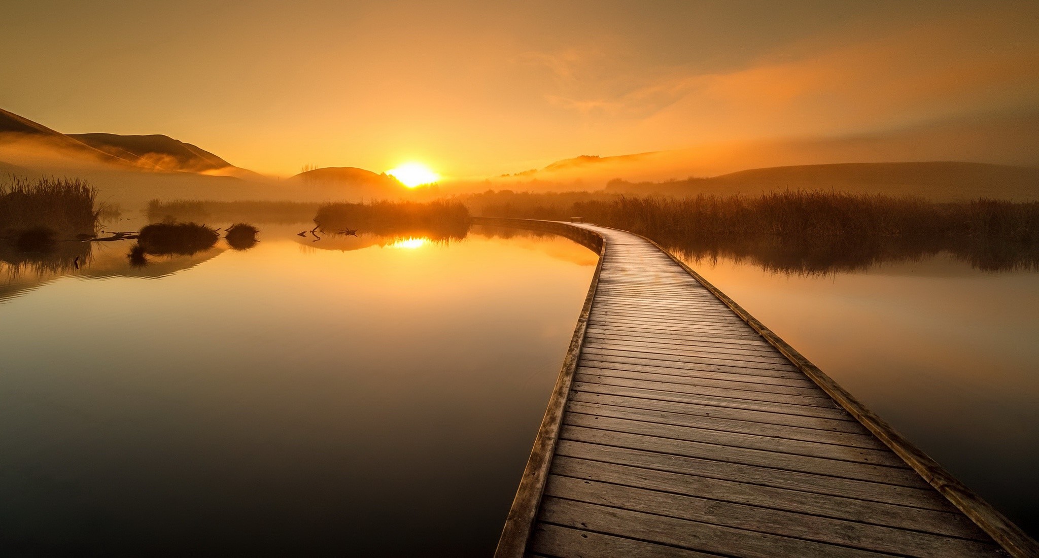 Wooden boardwalk over water at sunrise with mist HD Wallpaper