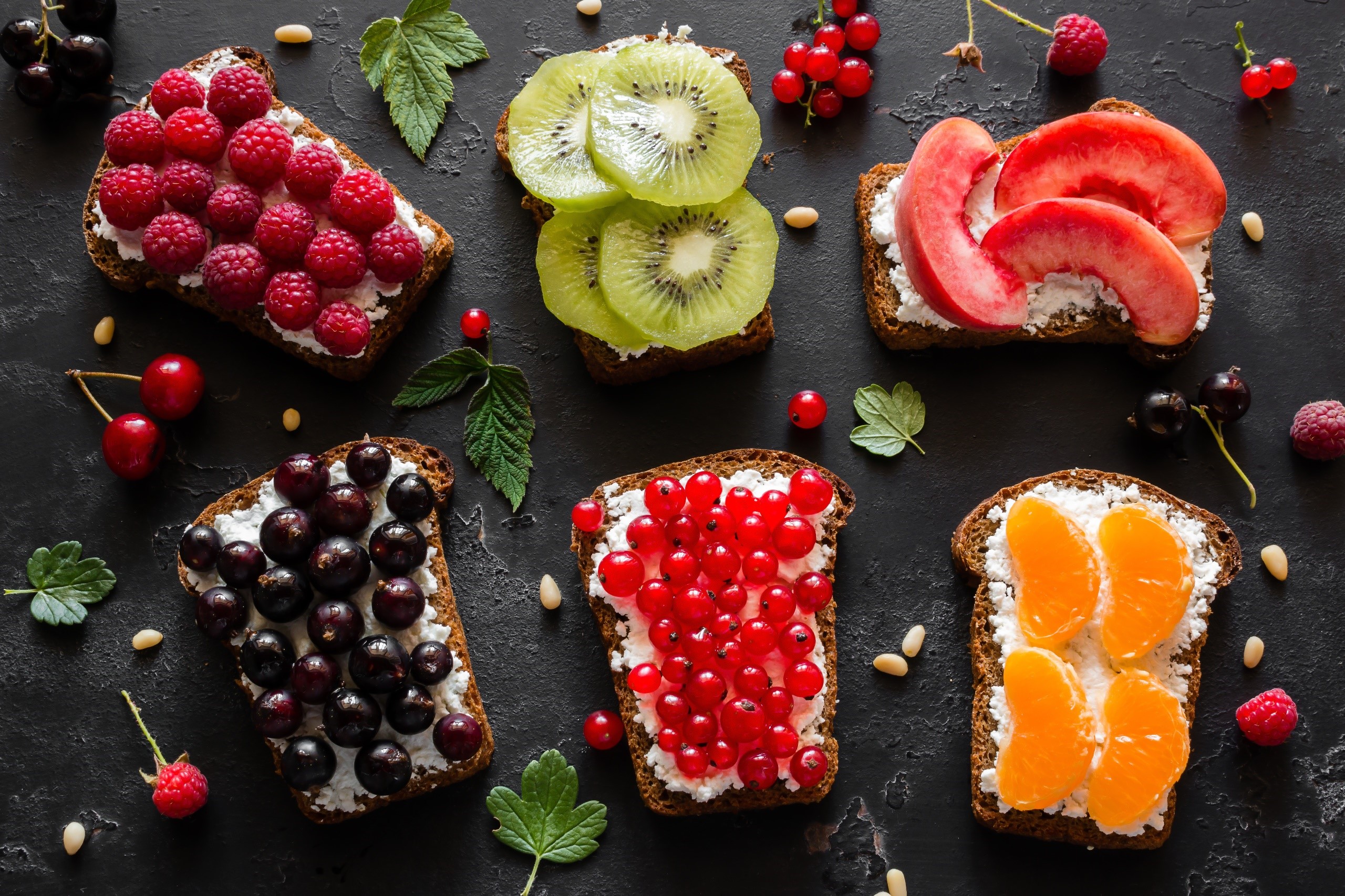 Assortment of fruit toasts with cream cheese on dark background HD Wallpaper