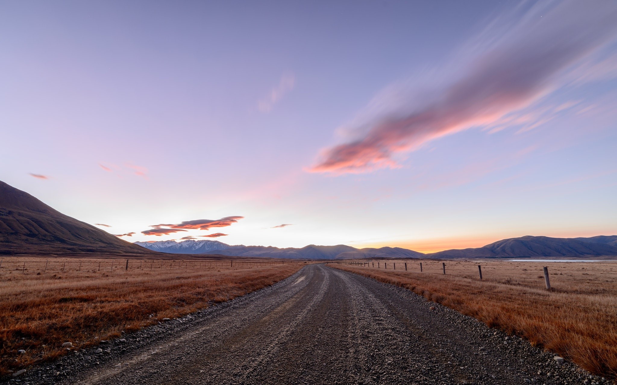 Dirt road through plains at sunset with mountains HD Wallpaper