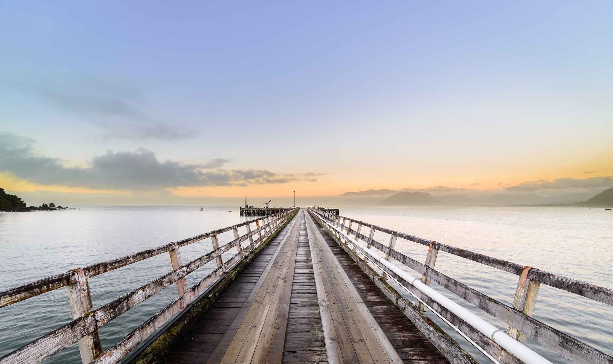 Wooden pier extending into the ocean at sunrise HD Wallpaper