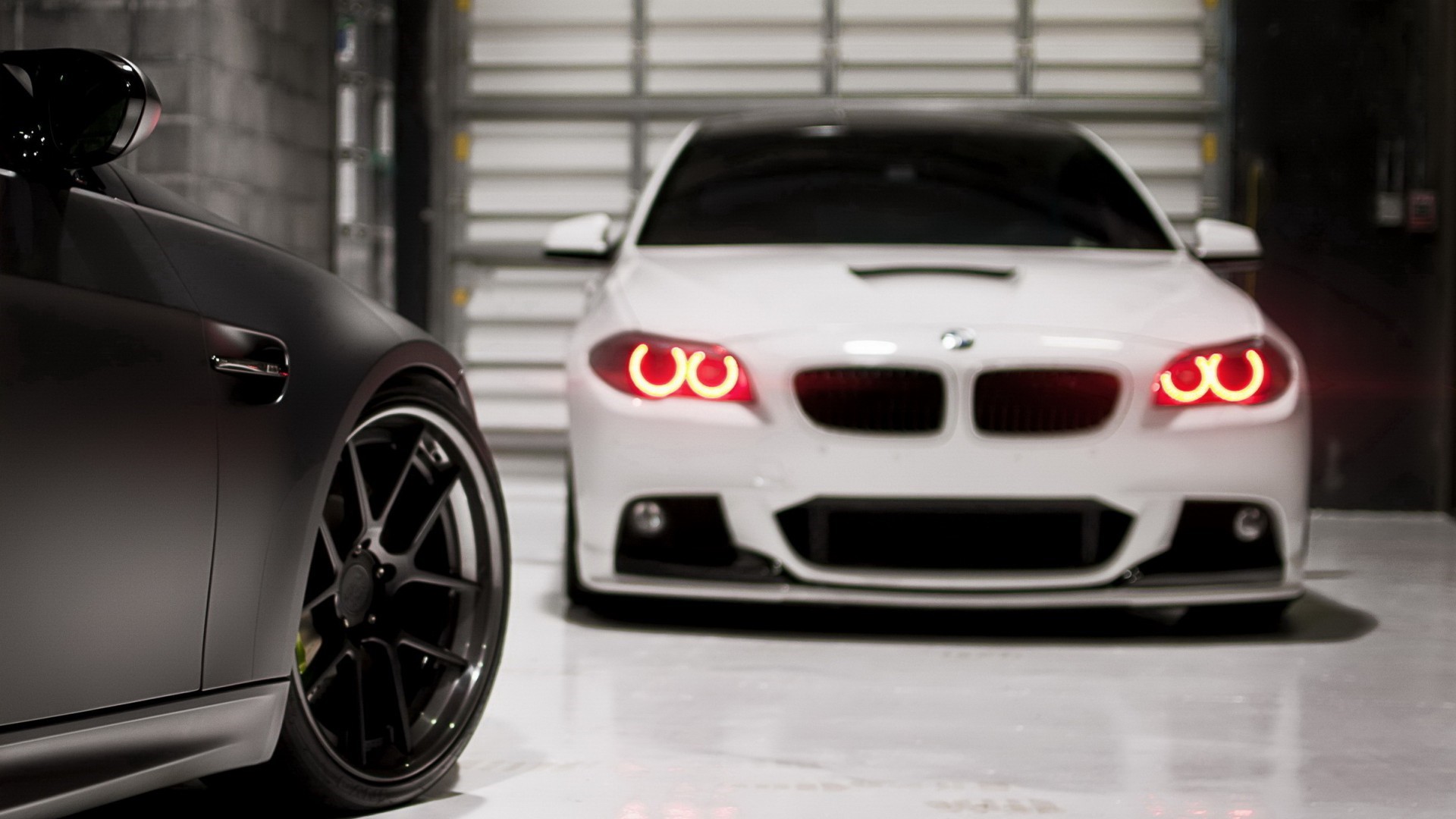 Two BMW cars in a garage, one black, one white HD Wallpaper