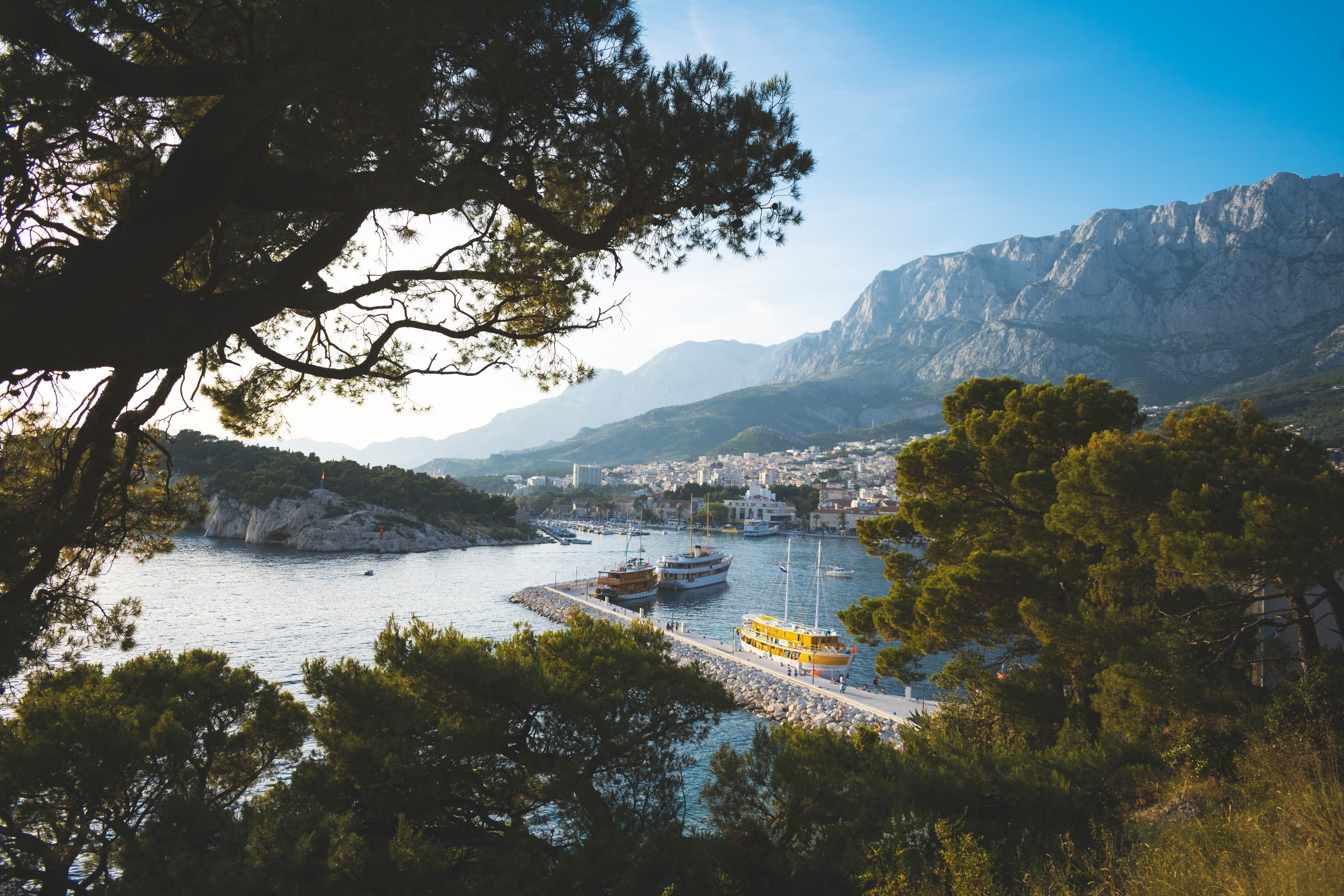 Boats docked in a harbor with mountains in the background HD Wallpaper